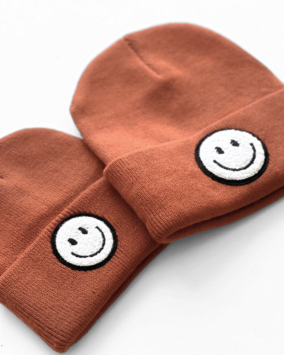 Smiley Beanie in rust color featuring playful smiley face embroidery, perfect for cozy everyday wear.