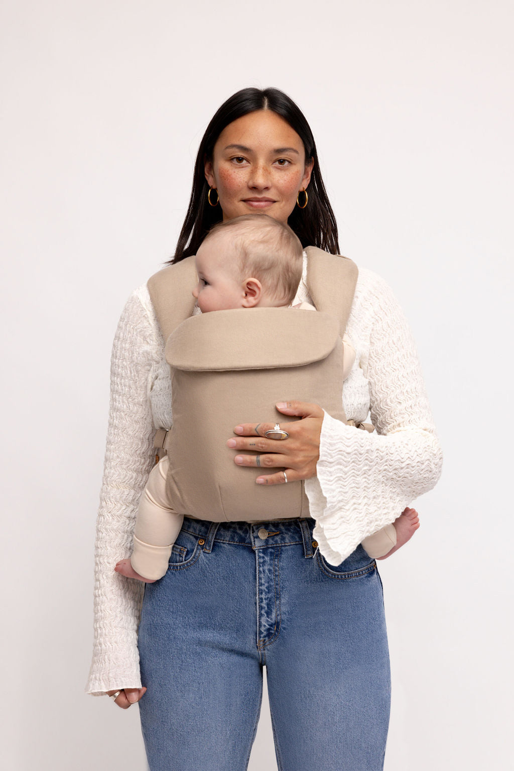 Woman wearing a taupe grey Desert Lark Aerial Carrier with a baby, showcasing comfort and style.