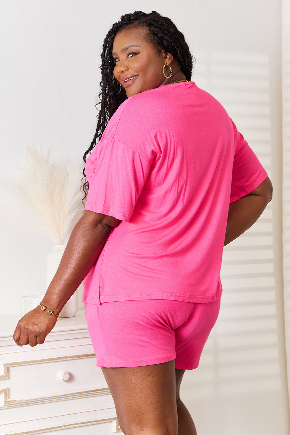 Woman in a pink half-sleeve top and shorts set, showcasing a relaxed fit and comfortable style.