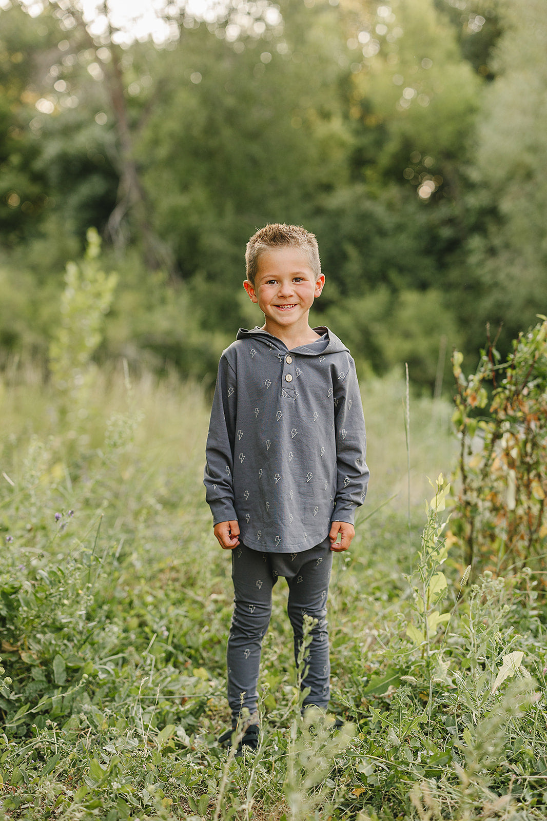 Boy in a stylish boys lightning bolt school outfit, wearing a hooded set in nature, ready for school adventures.