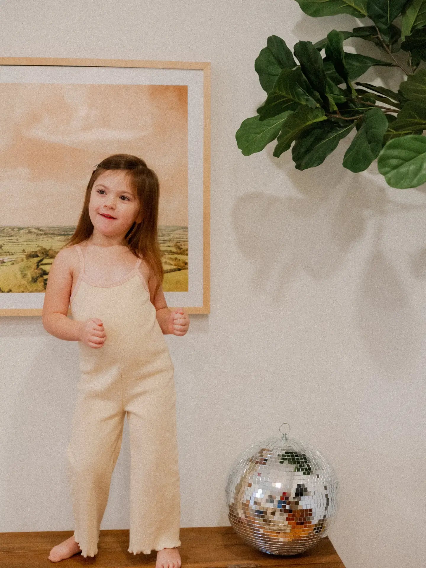 Little girl in creamy neutral ribbed jumpsuit, showcasing cozy baby style with playful vibes.