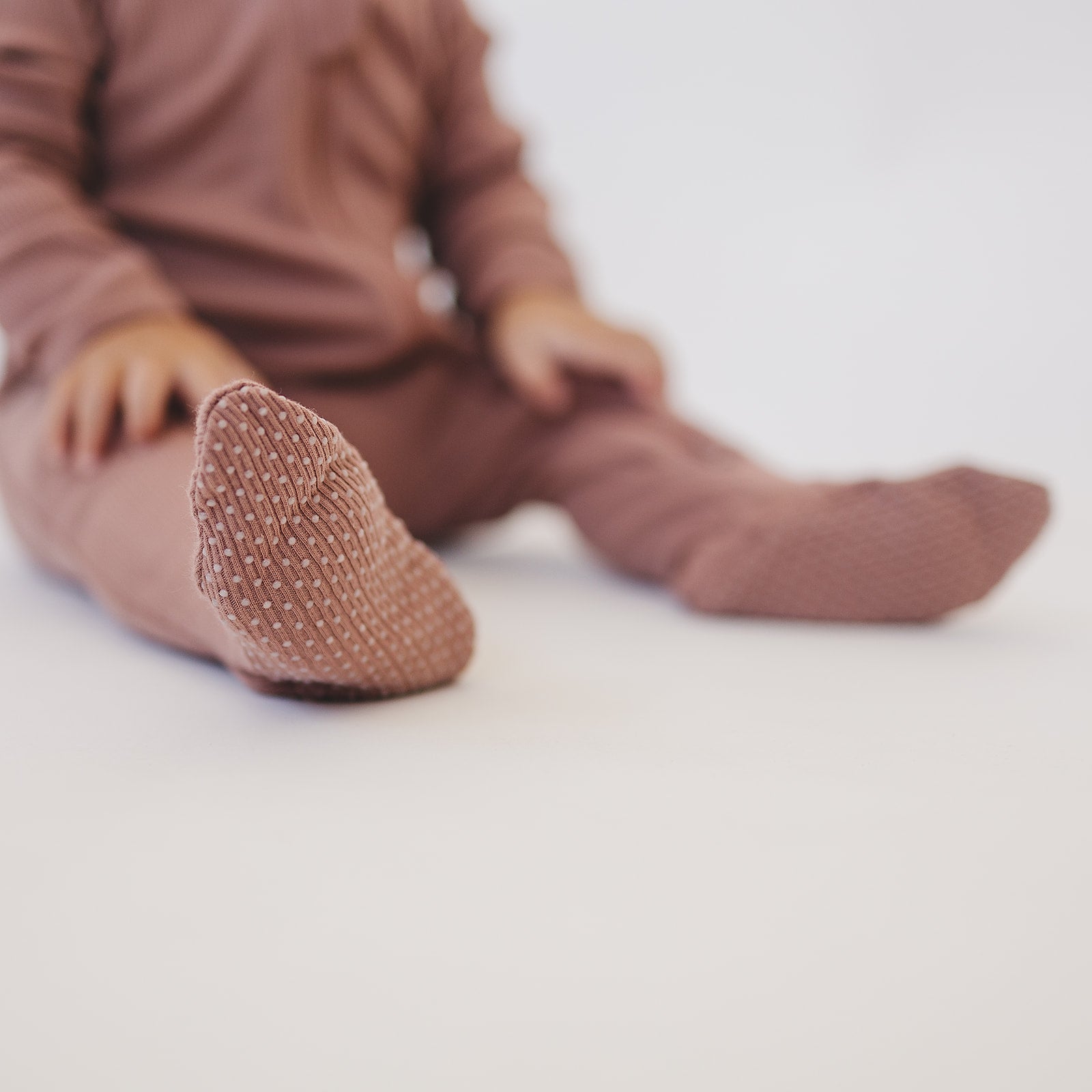 Organic baby zipper sleeper in dusty rose color, featuring ribbed fabric and cozy fold-over cuffs.