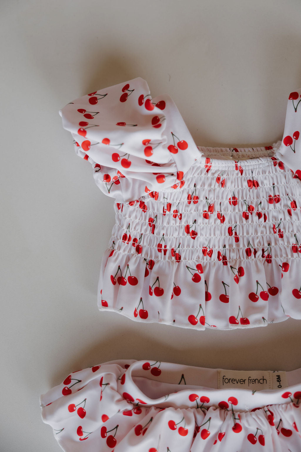 Two piece cherry print swimsuit top with ruffle accents for kids. Adorable and trendy summer swimwear.