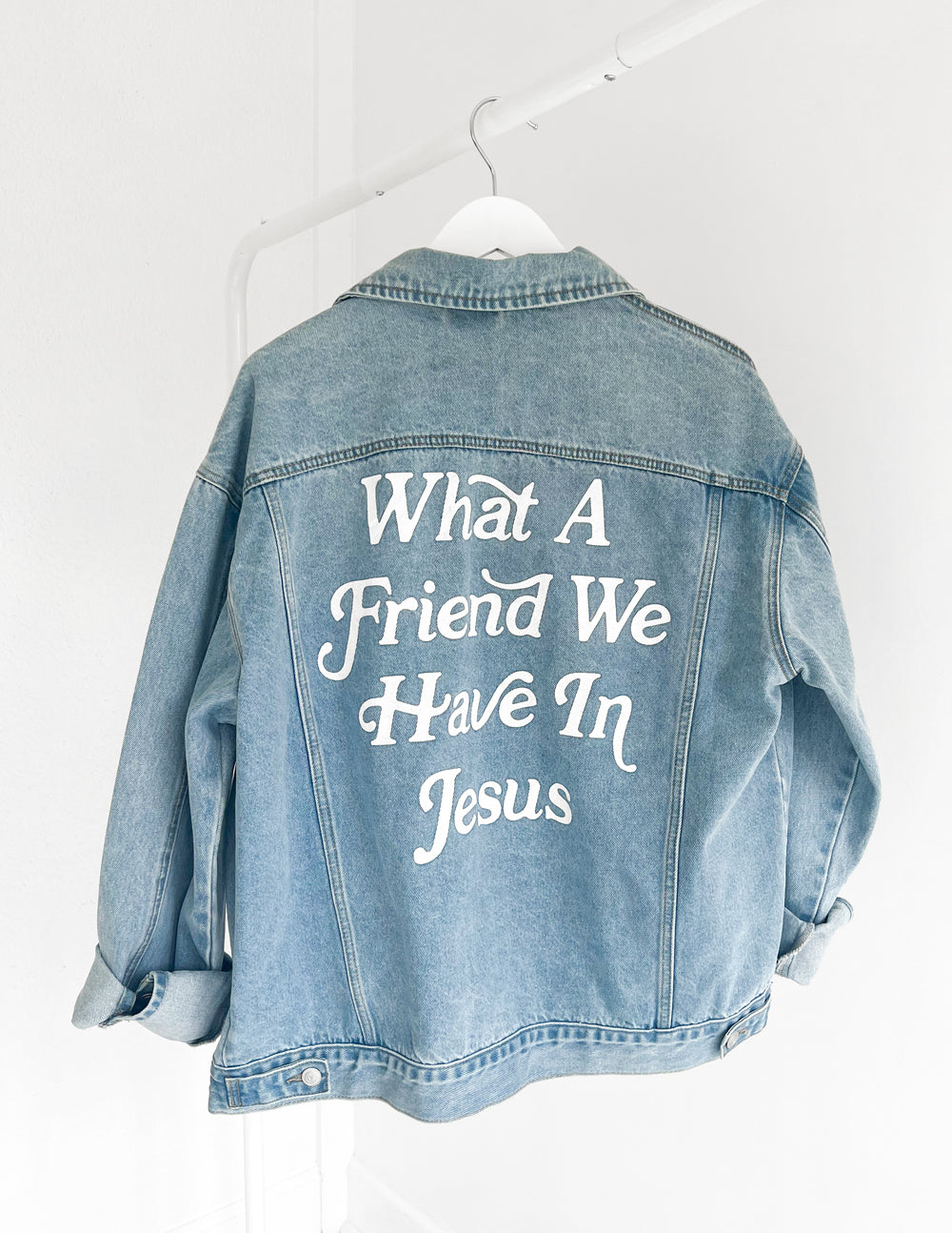 What a Friend in Jesus denim jacket for women featuring bold white lettering on back, stylish faith-based apparel.