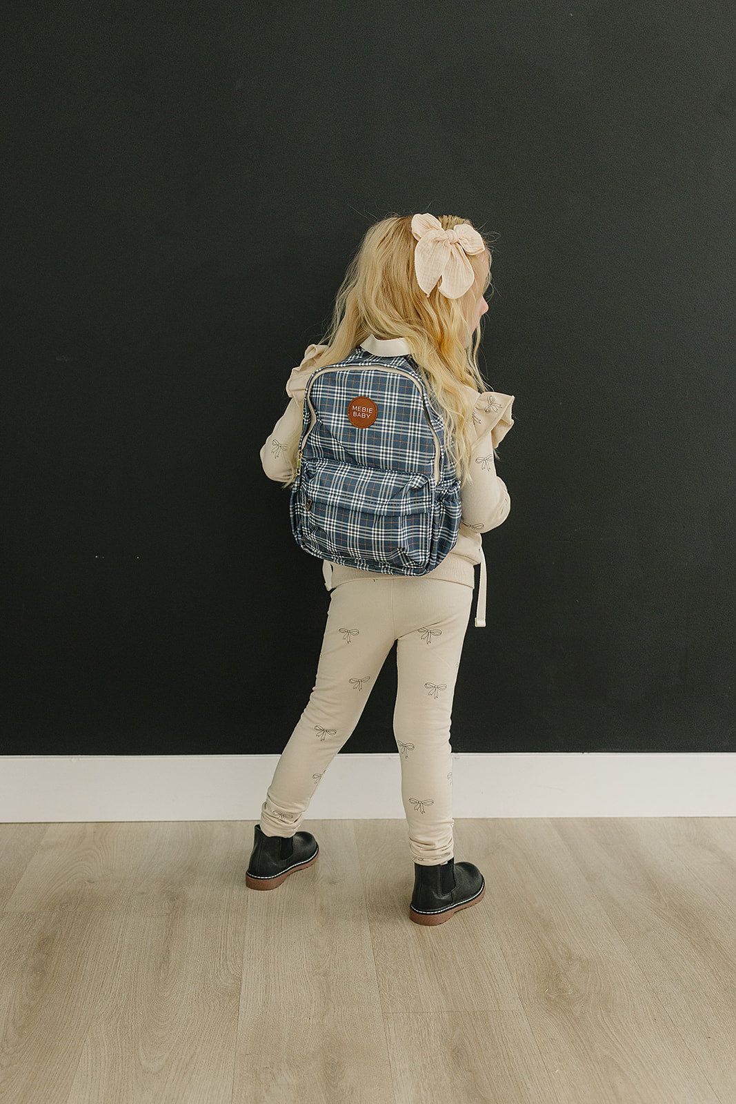 Girl wearing a navy plaid mini backpack, perfect for kids, ideal for daycare and weekend adventures.