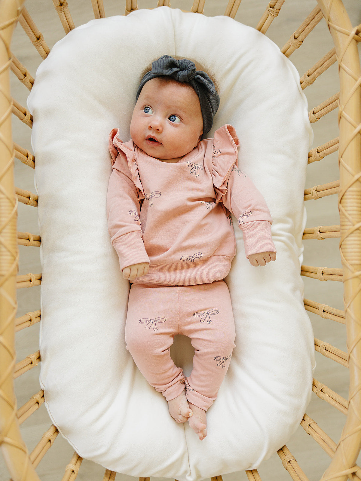 Infant wearing a pink ribbon ruffle set, featuring a soft pink sweatshirt with ruffles and matching leggings.