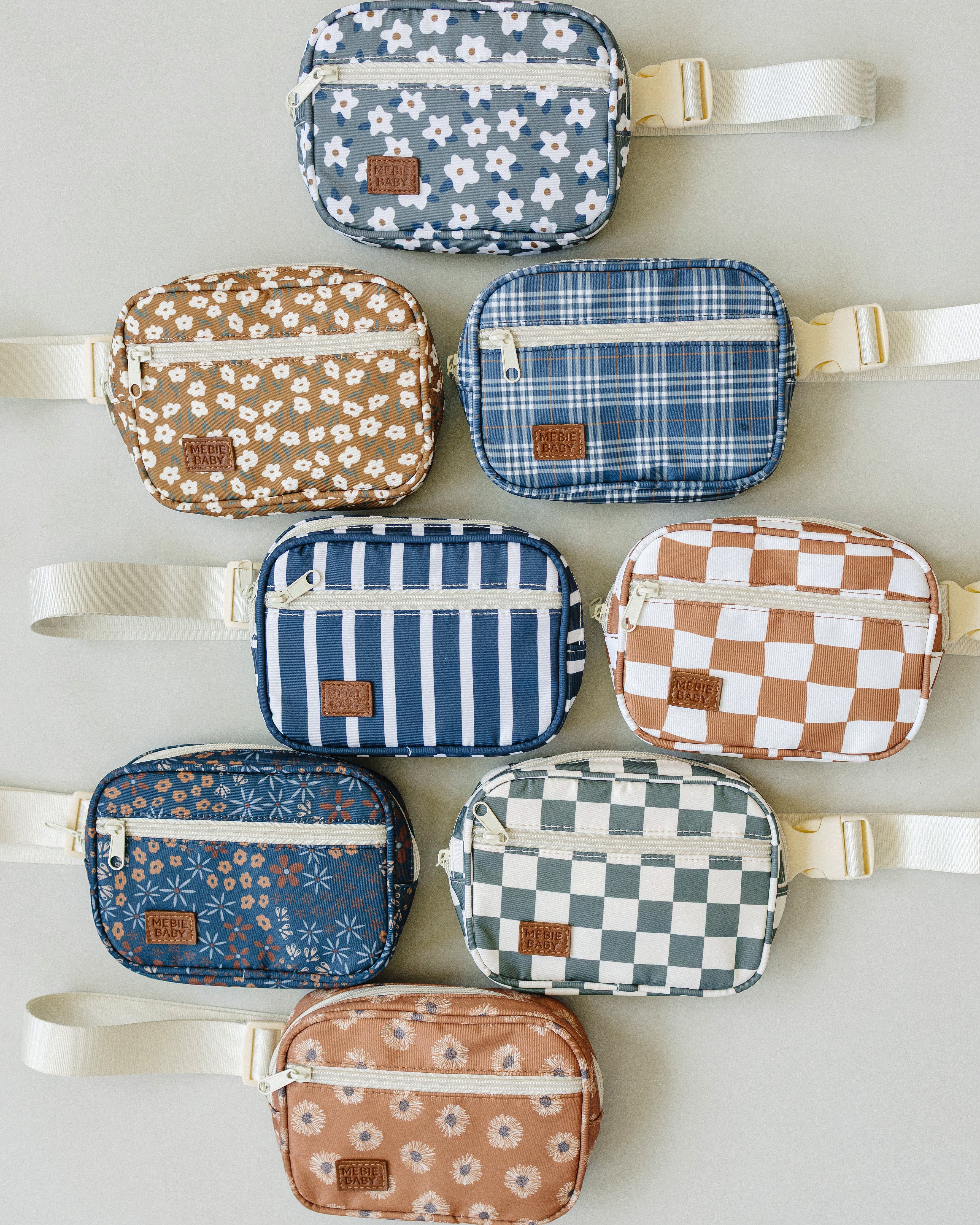 Assorted colorful fanny packs in various patterns, showcasing designs including floral, stripes, and checks.