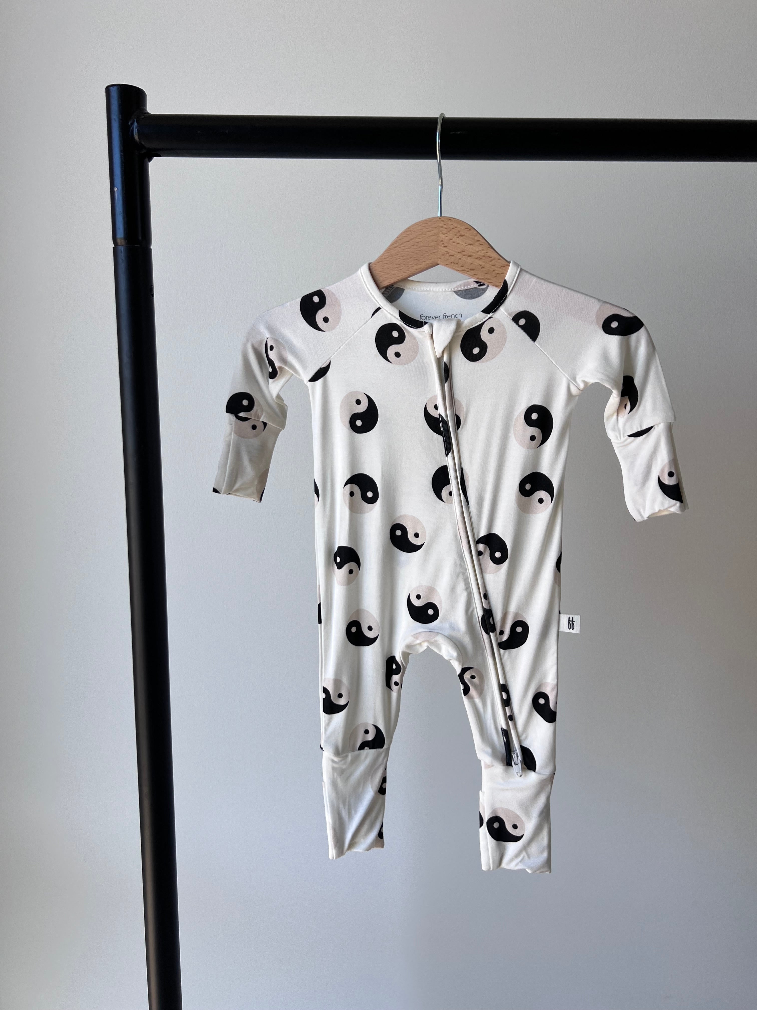 Black & White Yin Yang Bamboo Zip Baby Pajamas hanging on a rack, perfect for cozy and stylish comfort.