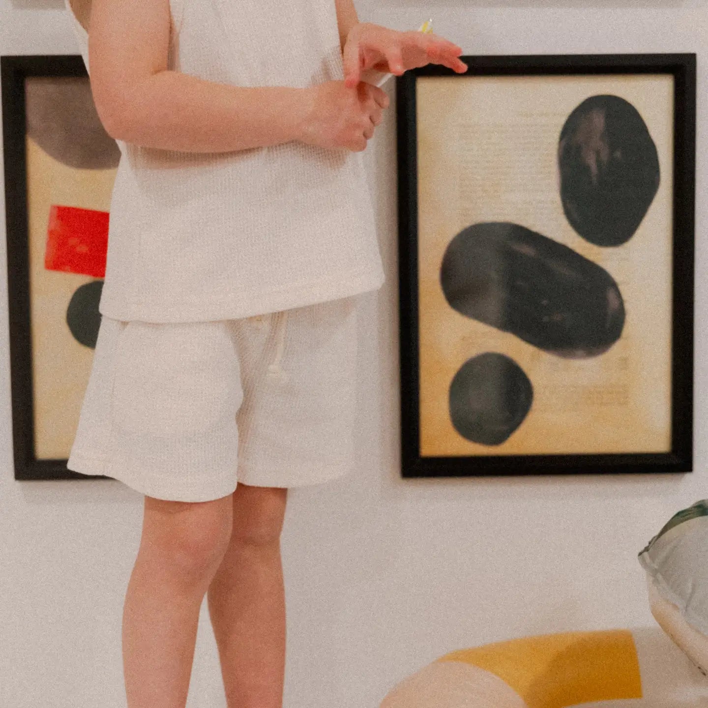 Child wearing the Madden Tank Set in cream, featuring a waffle-knit tank and matching shorts, standing beside abstract art.