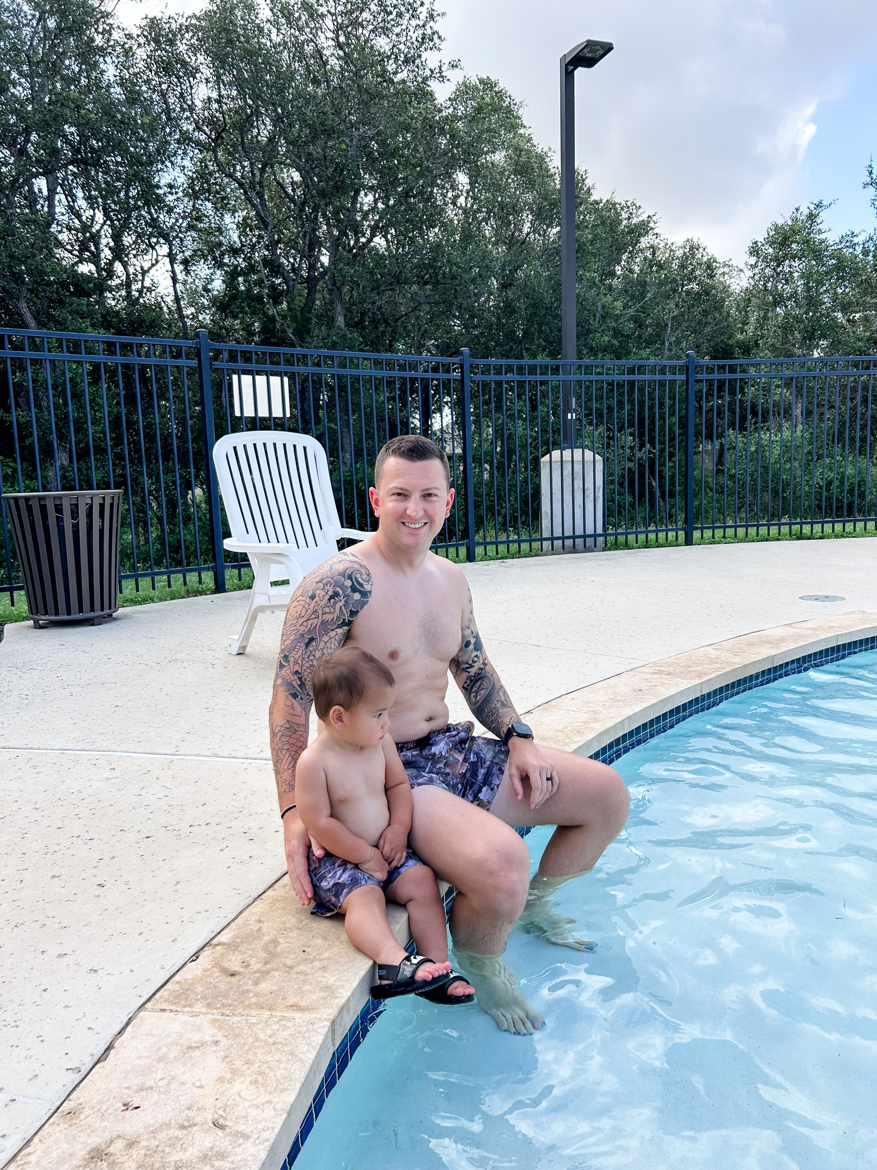 Dad and toddler enjoying pool time together, wearing camo swim shorts, ready for summer fun and water play.