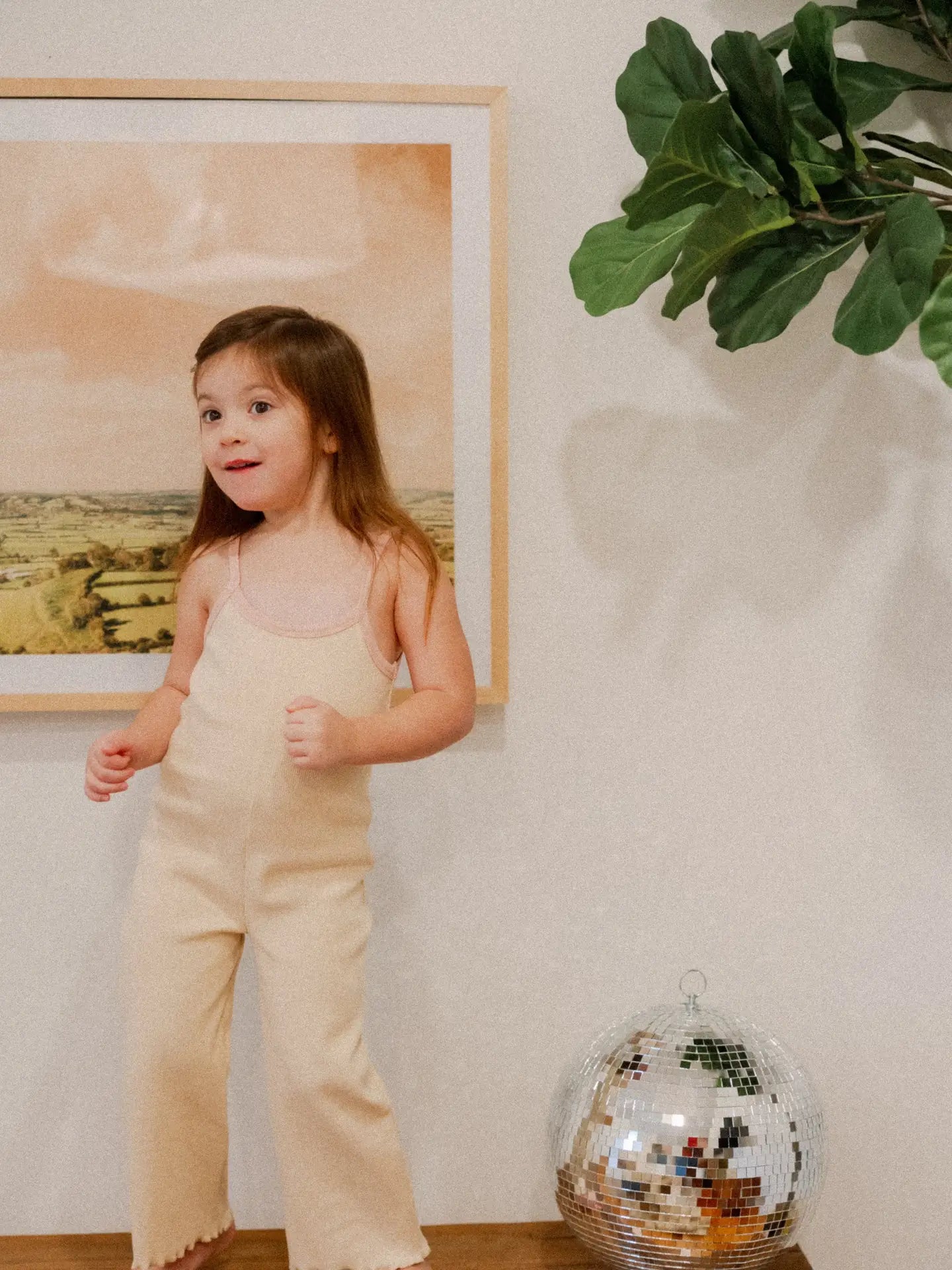 Adorable child wearing the Eloise ribbed jumpsuit in cream, showcasing a cozy, minimalist baby fashion style.