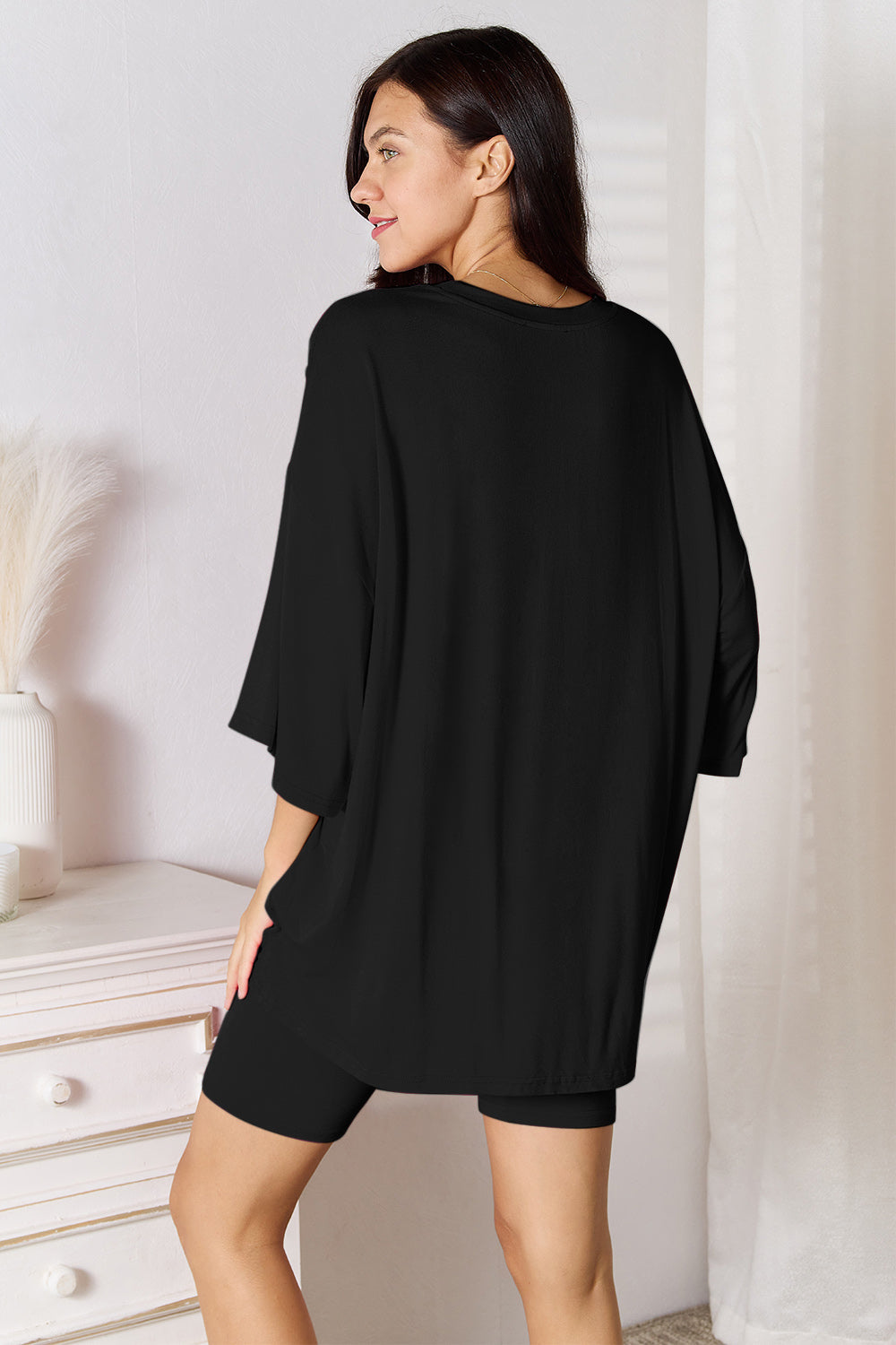 Woman wearing a black oversized bamboo t-shirt and matching shorts, showcasing a cozy, stylish loungewear look.