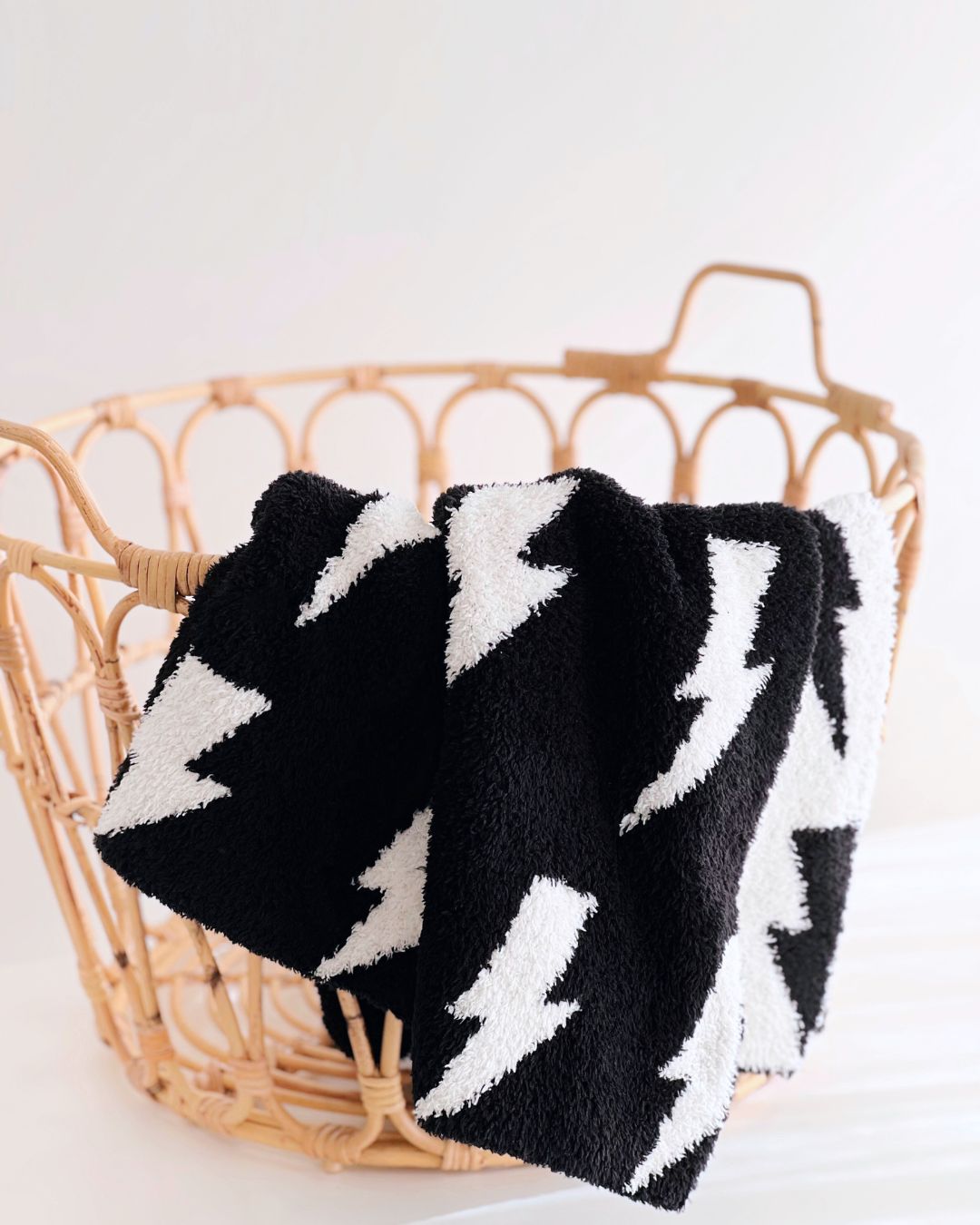 Lightning Bolt Fuzzy Blanket in black with white lightning designs, displayed in a woven basket.