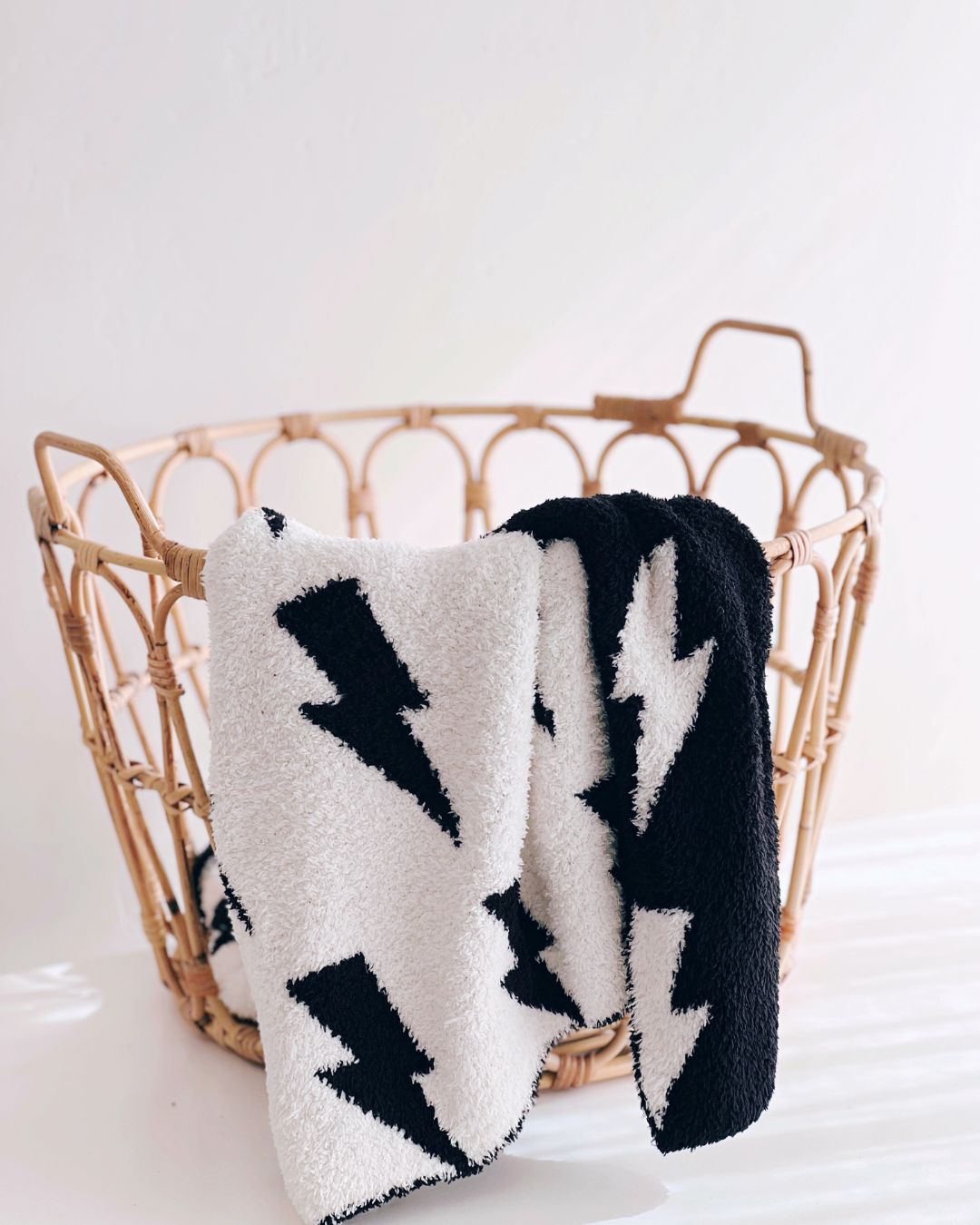 Lightning Bolt Fuzzy Blanket in black and white, cozy and plush, displayed in a woven basket.