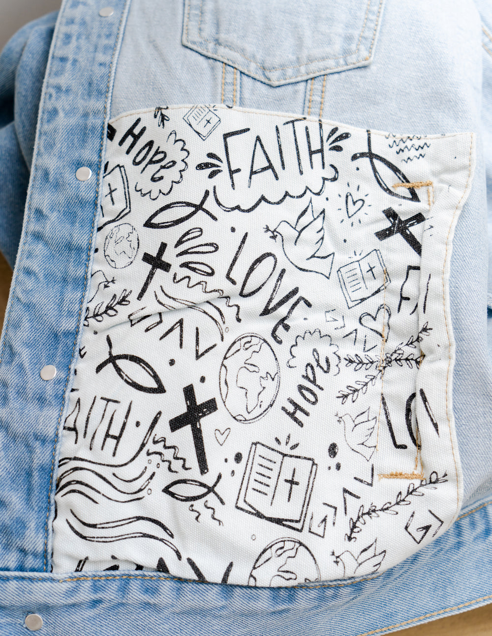 Inside of denim jacket featuring faith-inspired designs with words like 'Faith', 'Love', and Christian symbols.