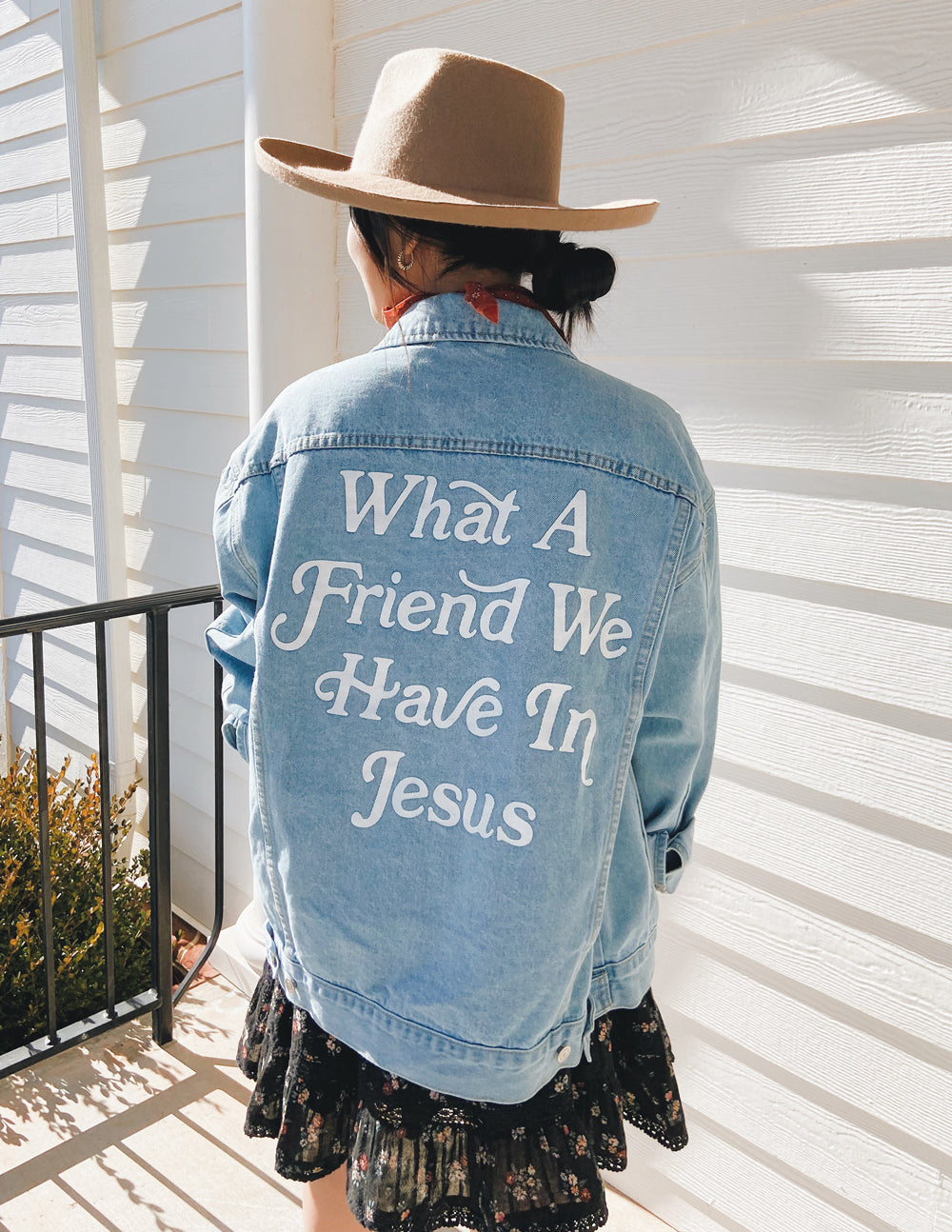 Woman wearing a denim jacket with bold 'What A Friend We Have In Jesus' lettering on the back.