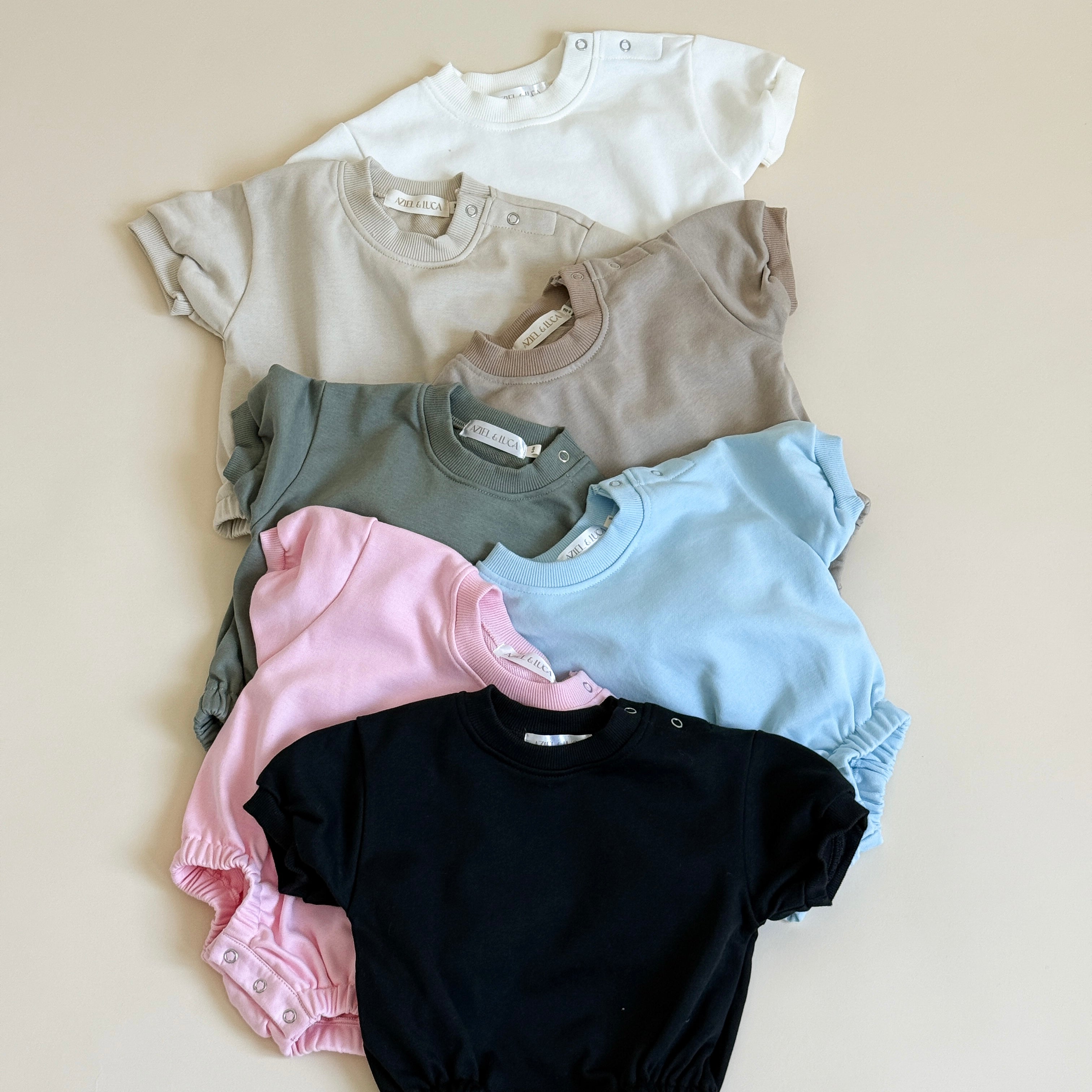 Short sleeve bubble rompers in various colors stacked together, lightweight and perfect for warmer weather.