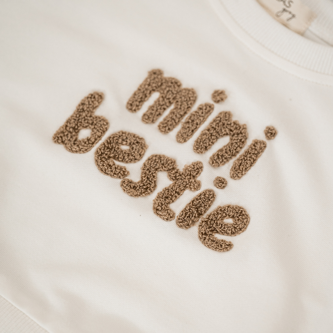 Mini Bestie Crewneck unisex baby sweatshirt featuring fuzzy terry-cloth embroidery in natural white.