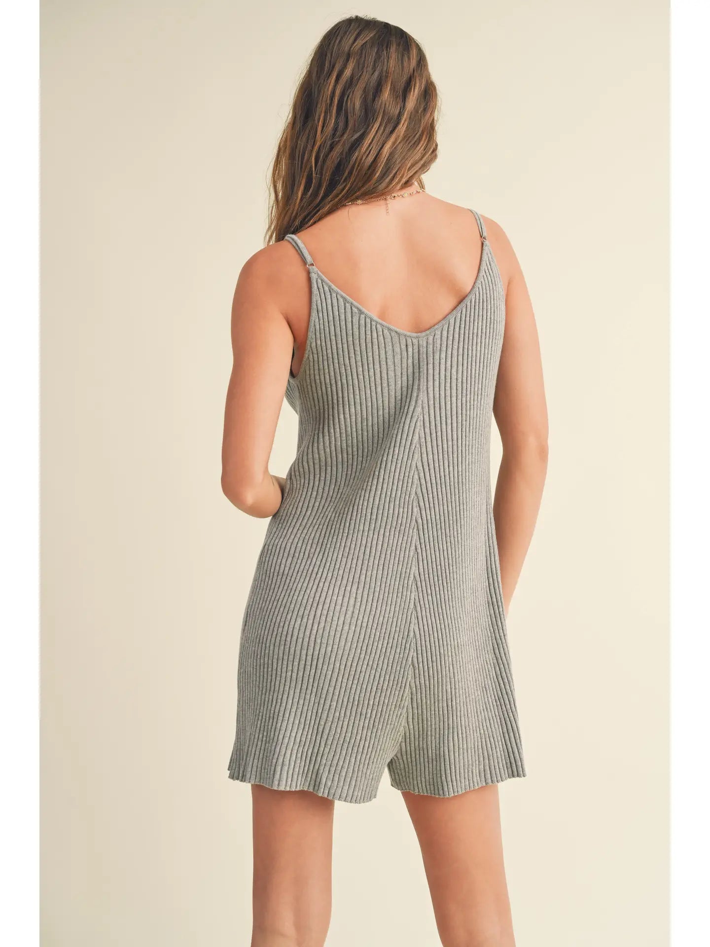 Back view of a woman wearing a ribbed knitted romper, showcasing its soft knit and flattering fit.