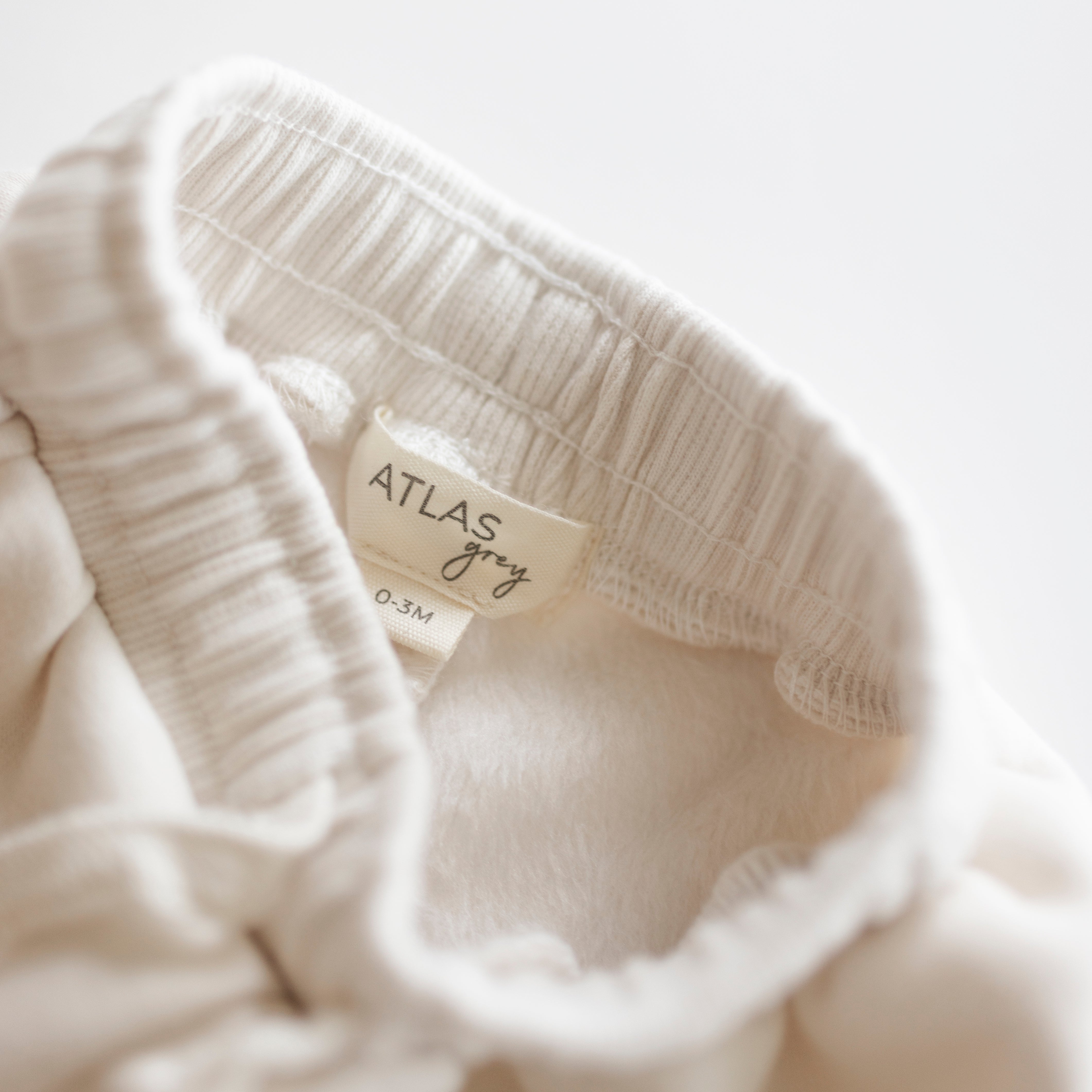 Close-up of the waistband and label of an Oversized Sweatpant for babies in soft neutral color.