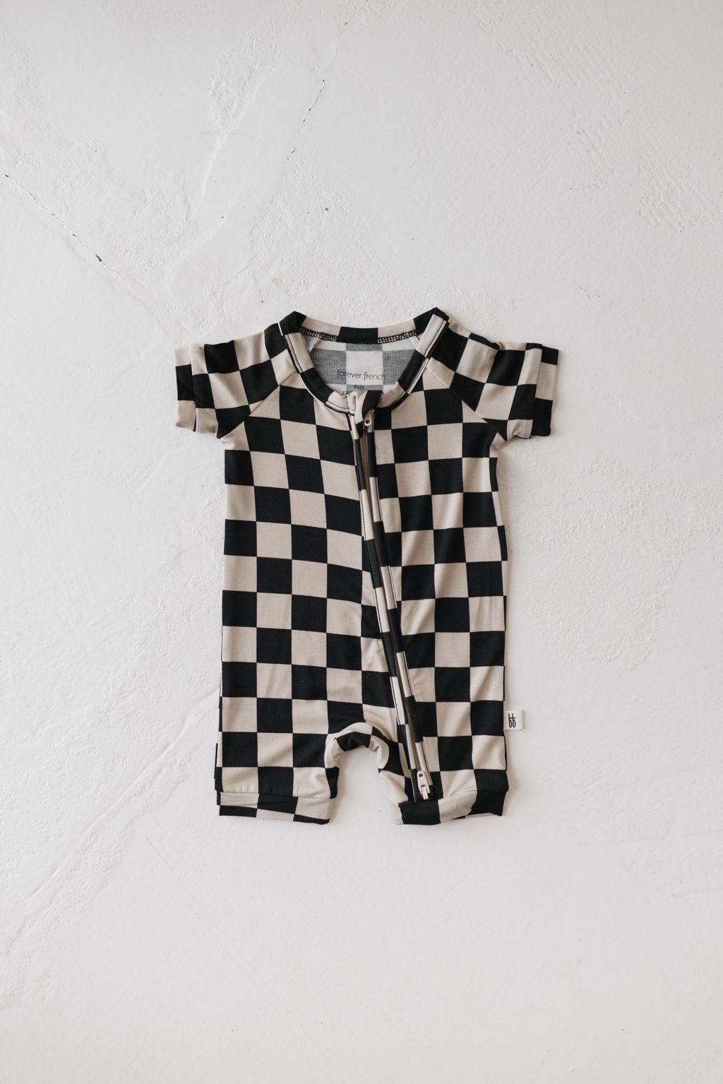 Black checkerboard bamboo zip shortie baby romper for summer, featuring short sleeves and a stylish design.