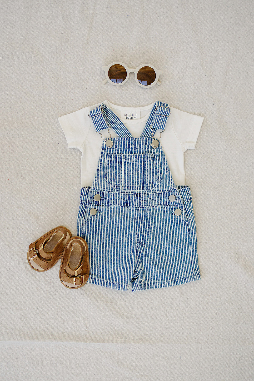 Blue stripe baby overalls set with white shirt, brown sandals, and stylish sunglasses, perfect summer toddler outfit.