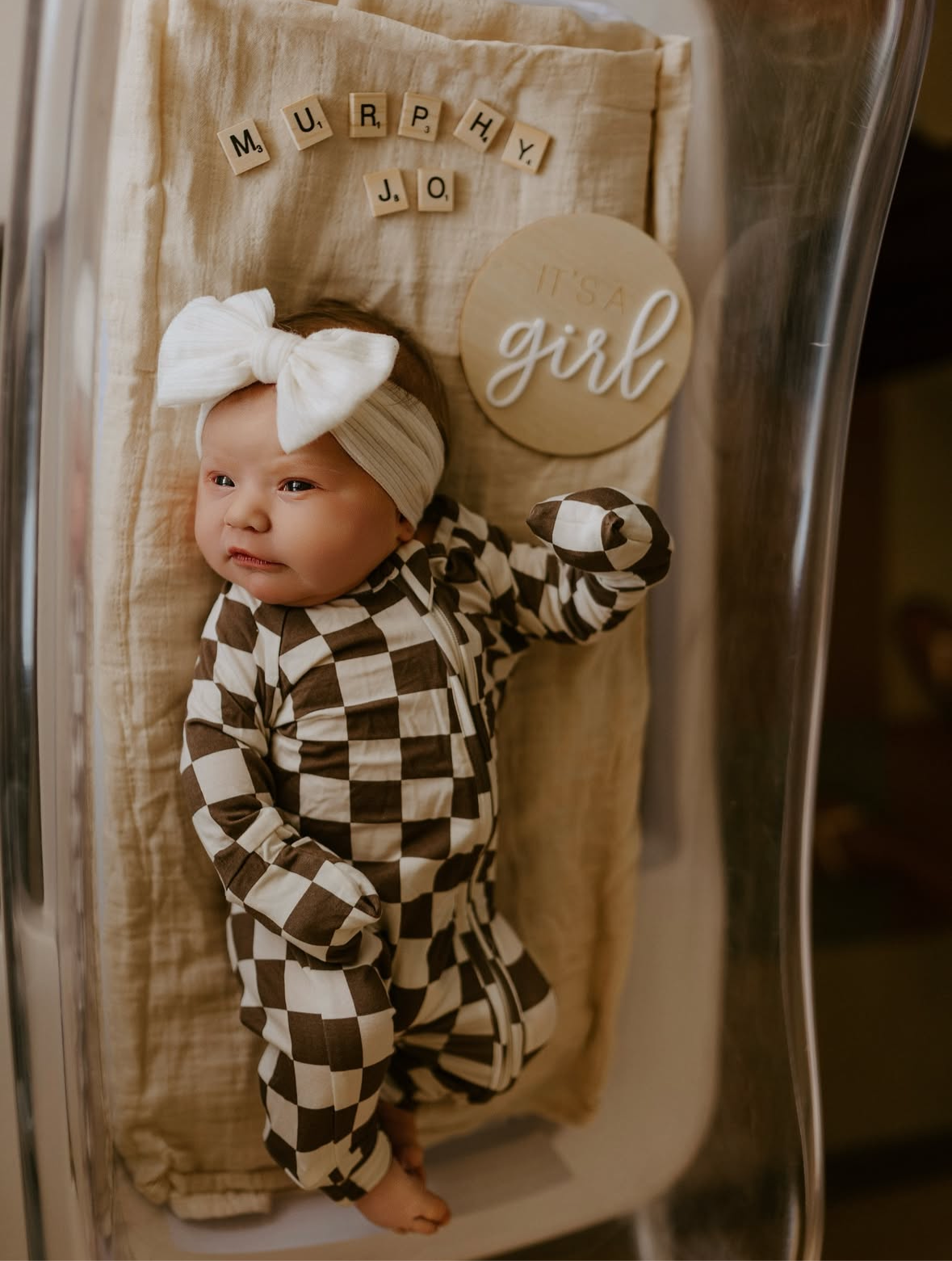 Baby wearing brown and white checkerboard bamboo zip pajamas by Dutton, showcasing cozy and stylish infant sleepwear.