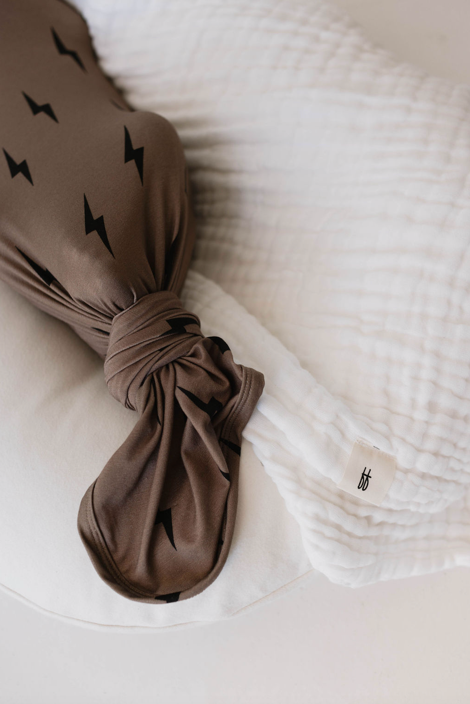 Bamboo Swaddle Black and Brown Lightning Bolt wrapped around a baby pillow with a white muslin blanket.
