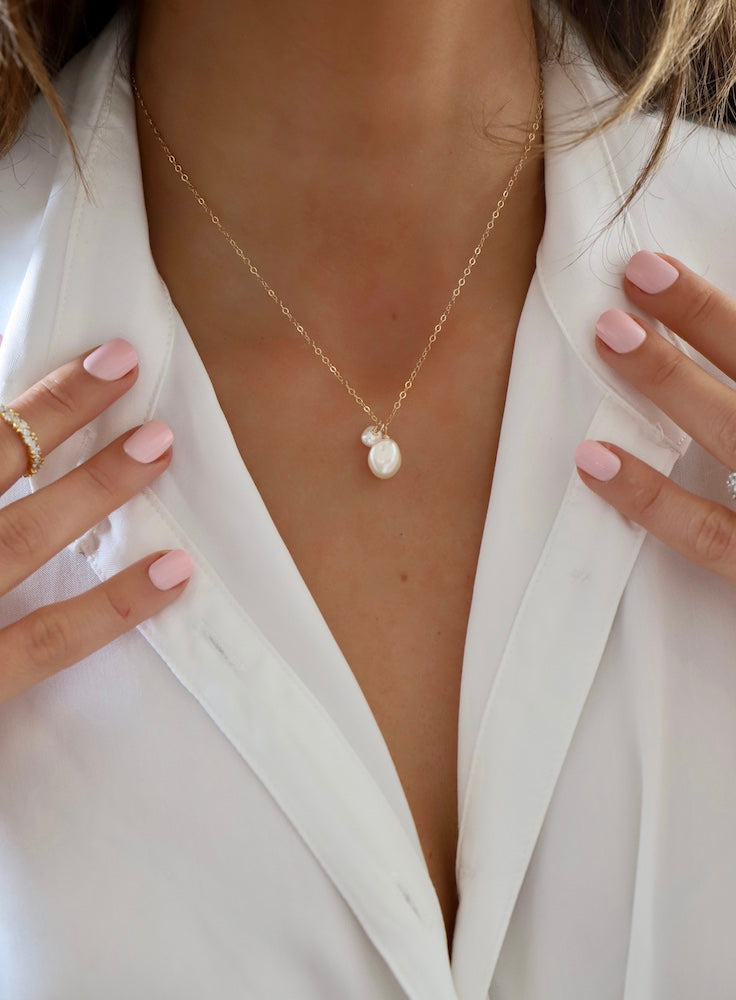 Double Pearl Drop Necklace showcasing delicate freshwater pearls on a gold-toned chain, worn with white blouse.