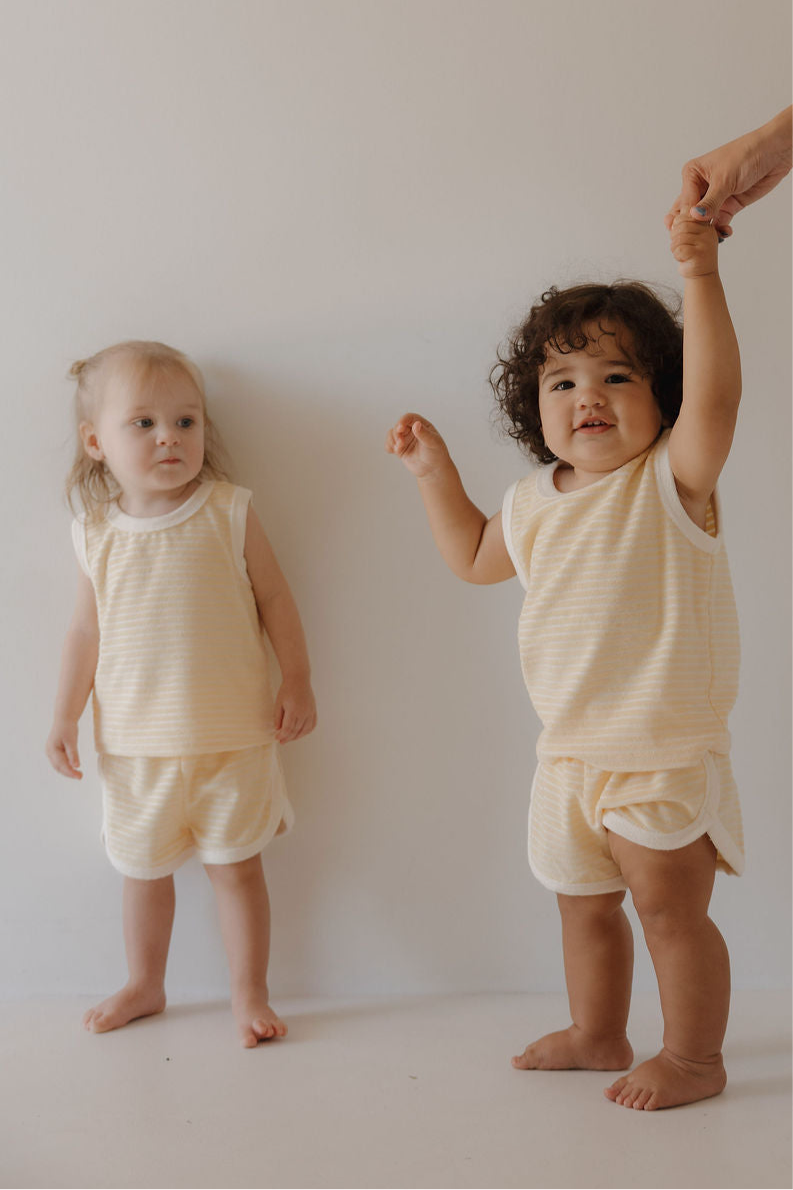 Two toddlers in soft creamsicle striped terry tank and short sets, showcasing a cozy and trendy summer look.
