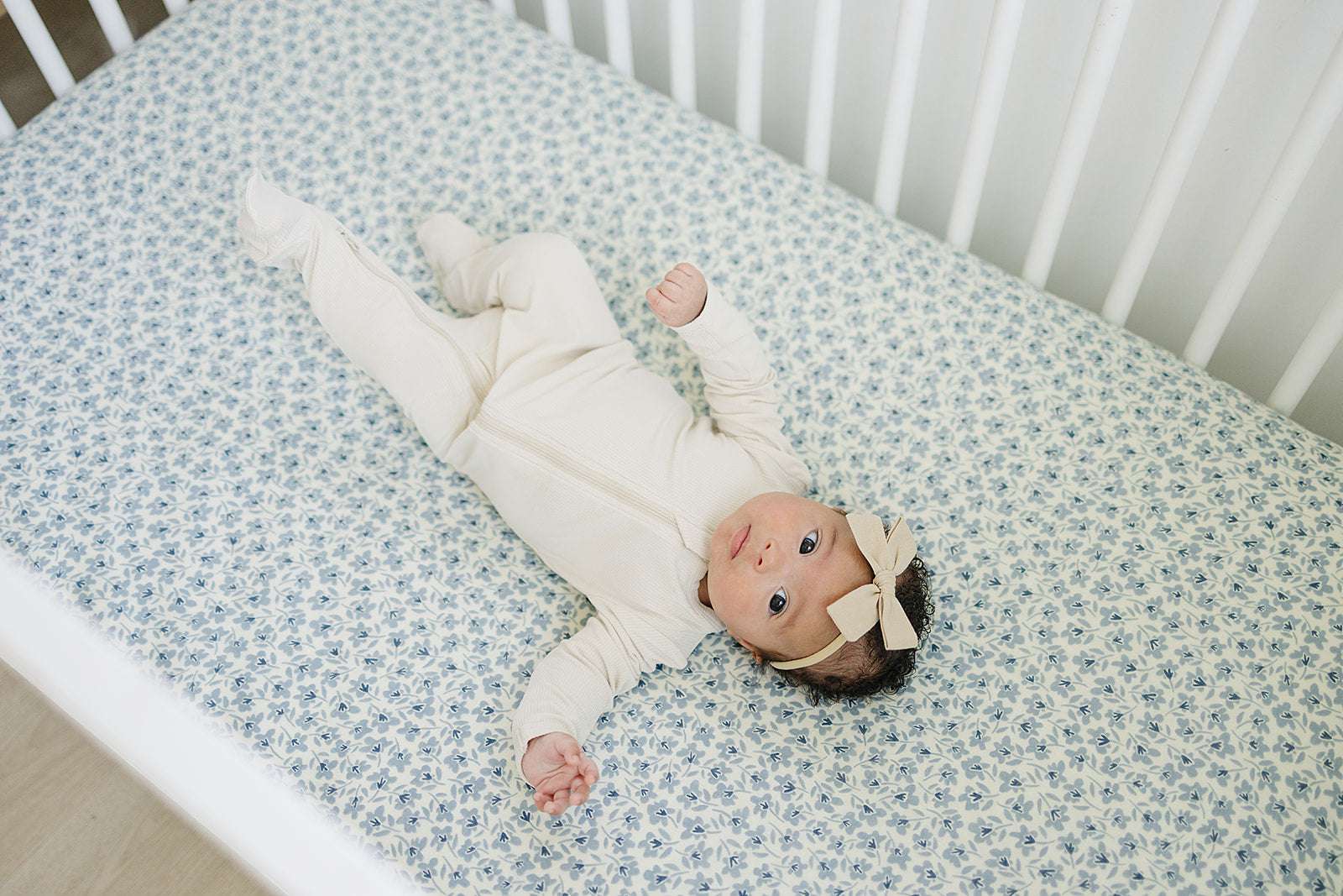 Muslin Crib Sheet in Blue Blossom with a baby lying on it, showcasing comfort and style for nursery decor.