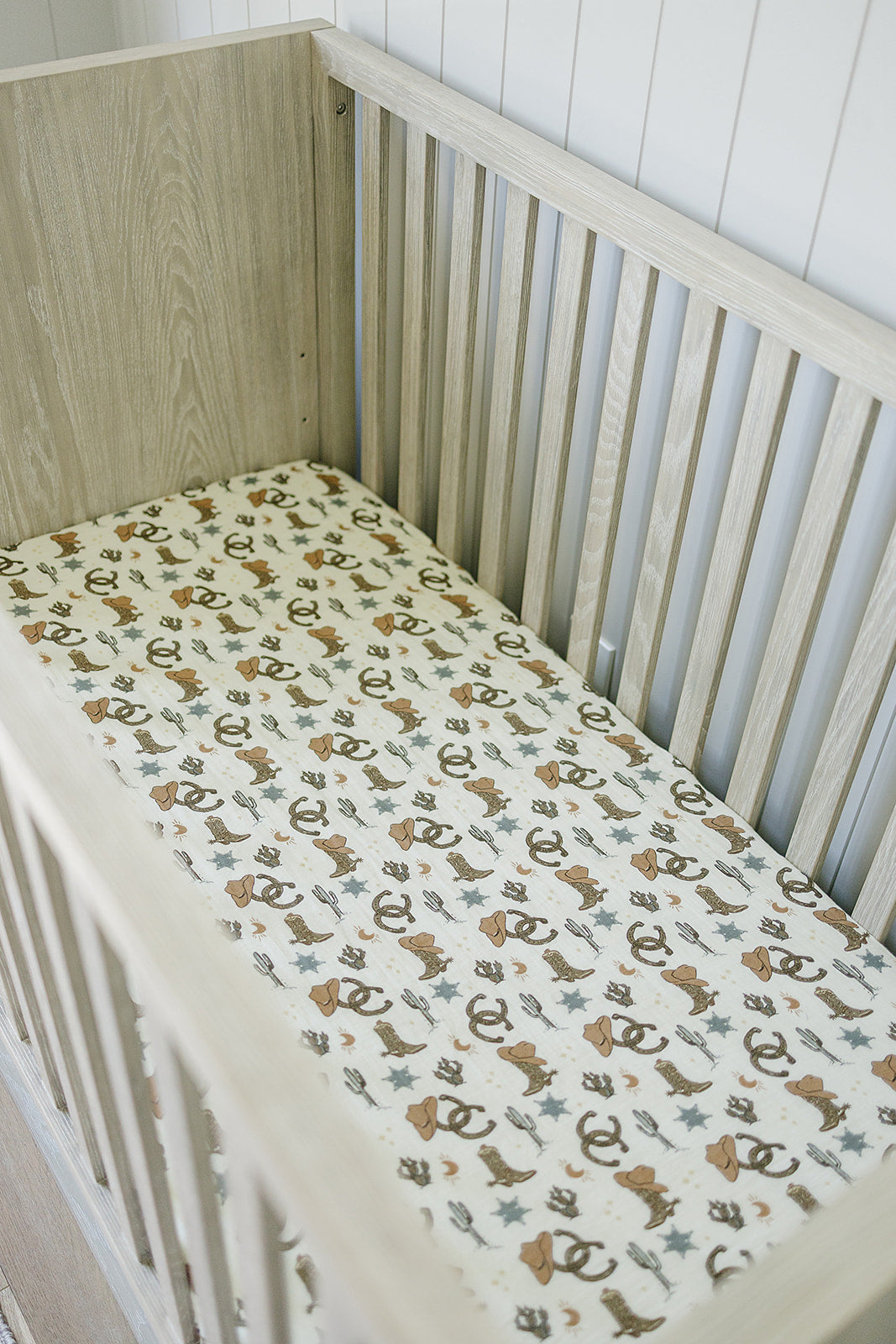 Muslin crib sheet Outlaw Cowboy on a crib mattress, showcasing playful western designs in soft cotton muslin.