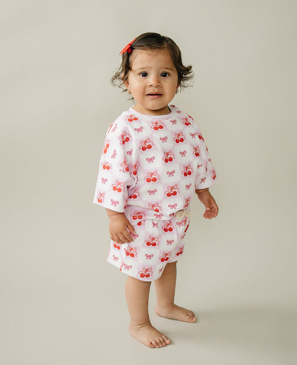 Toddler wearing a Checkered Cherry shorts set with playful cherry print, featuring a soft cotton blend for summer style.