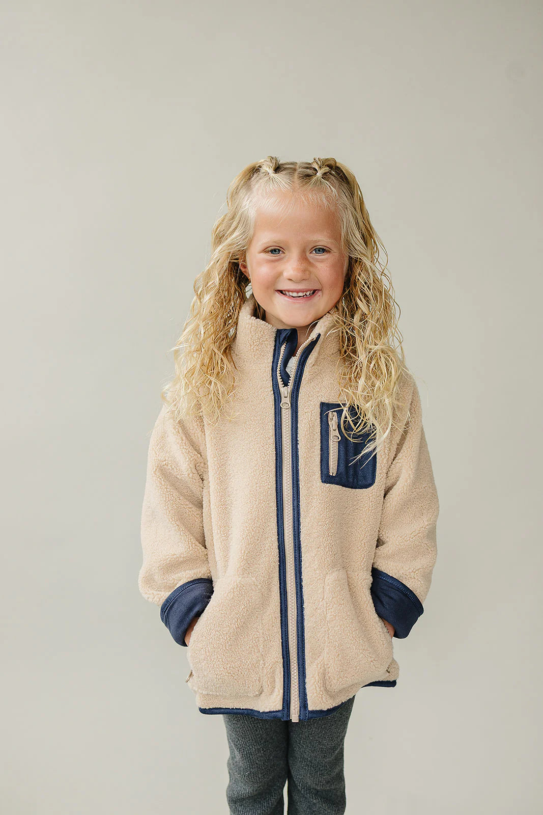 Baby and Kids Sherpa Zip-Up Jacket on a smiling girl with curly hair, perfect for chilly days.