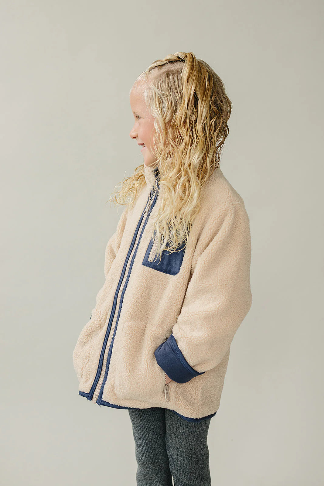 Child wearing a Baby and Kids Sherpa Zip-Up Jacket with a full zip front and hood for cozy warmth.