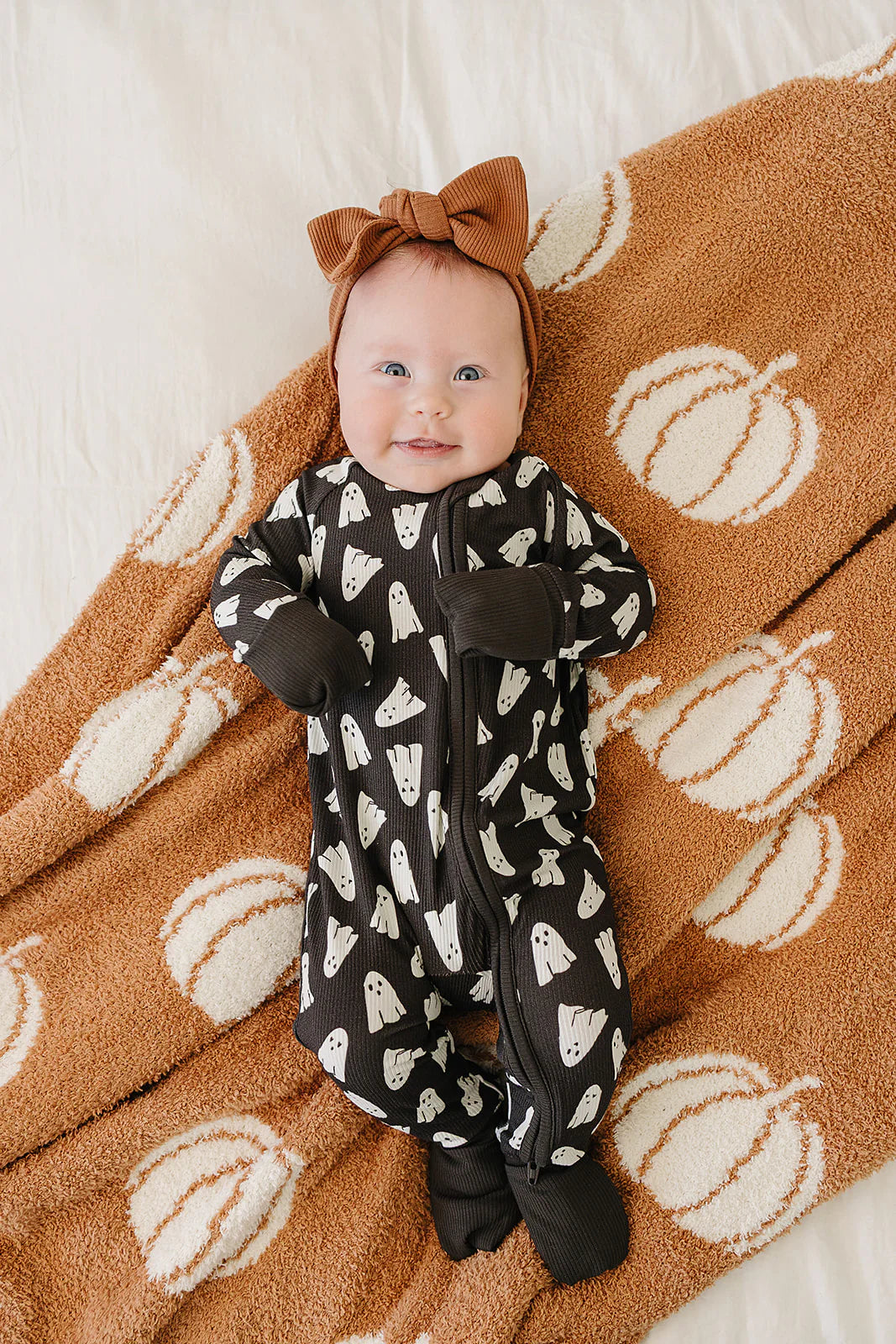 Bamboo Baby Pajamas Spooky Halloween featuring a baby in a ghost print outfit on a pumpkin blanket.