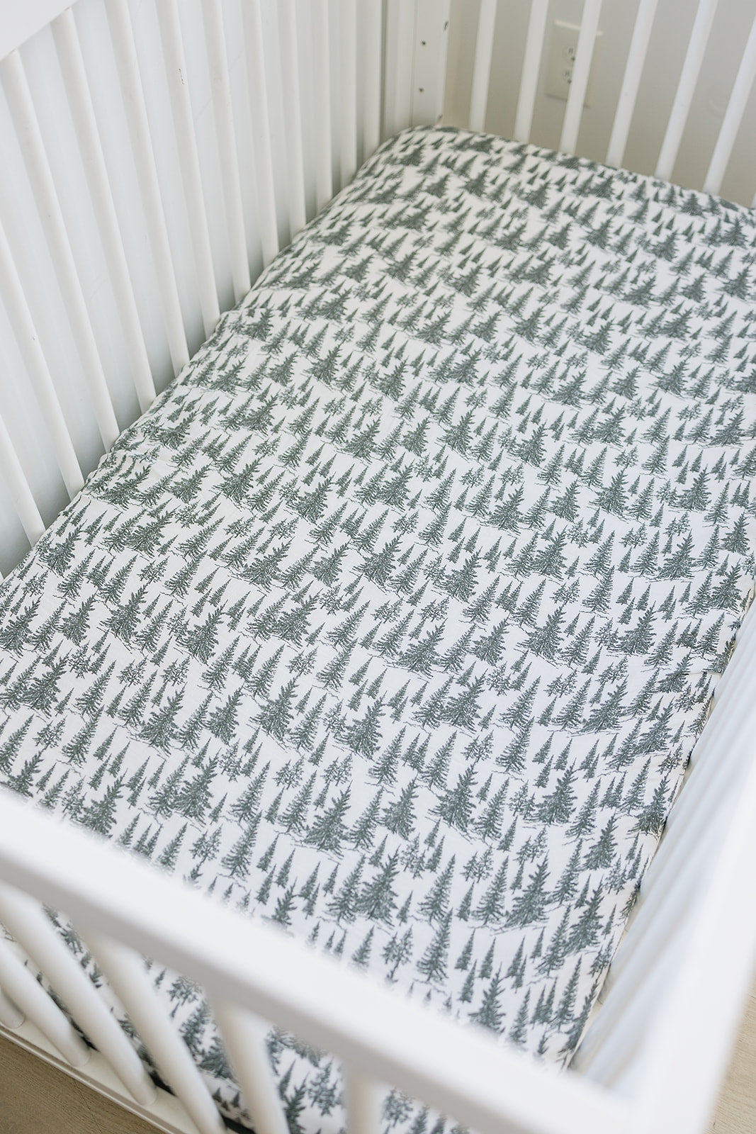 Muslin crib sheet featuring a forest woodland design, providing a cozy sleep space for babies.