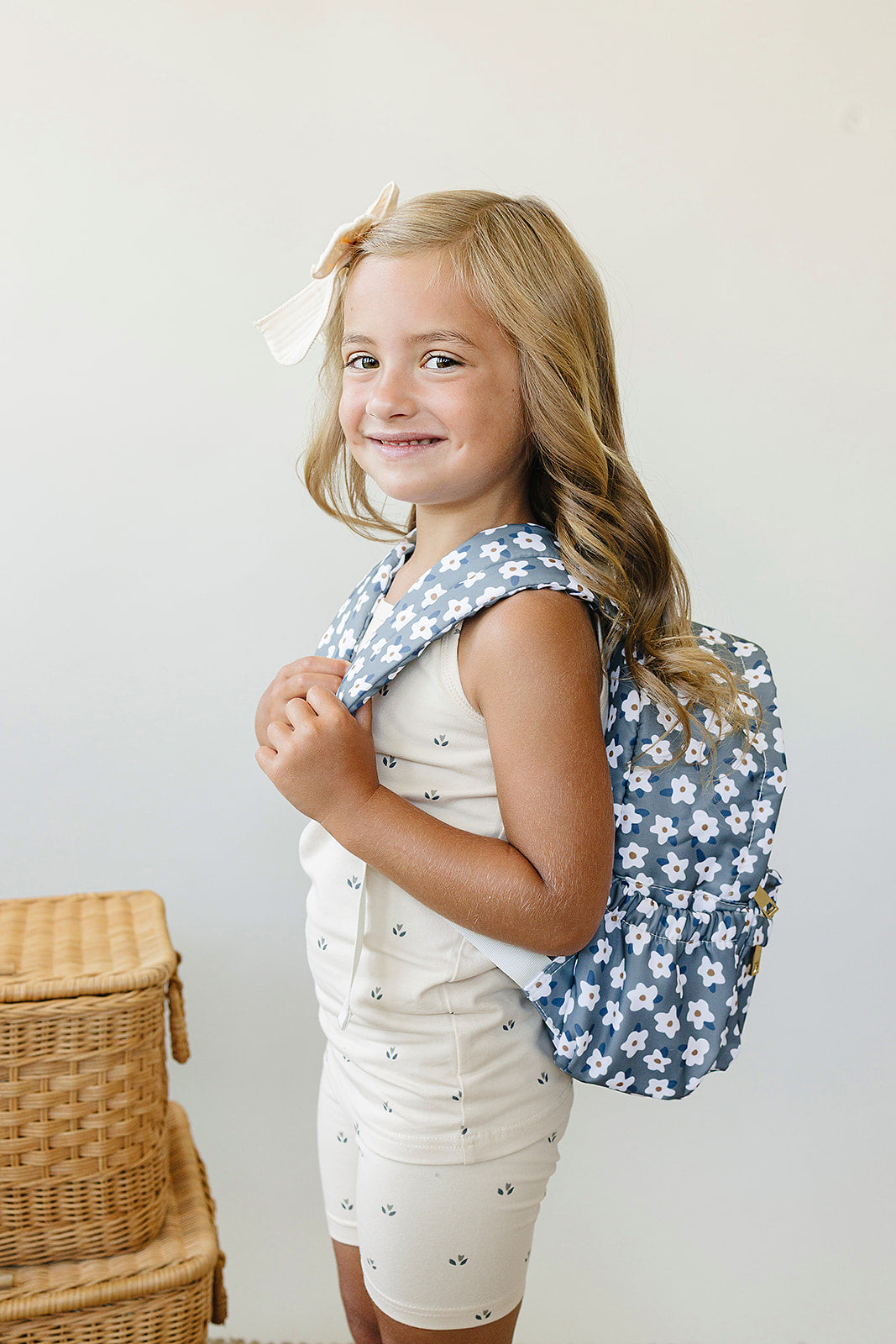 Cute girl wearing a kids mini backpack with a floral design, smiling and ready for preschool adventures.