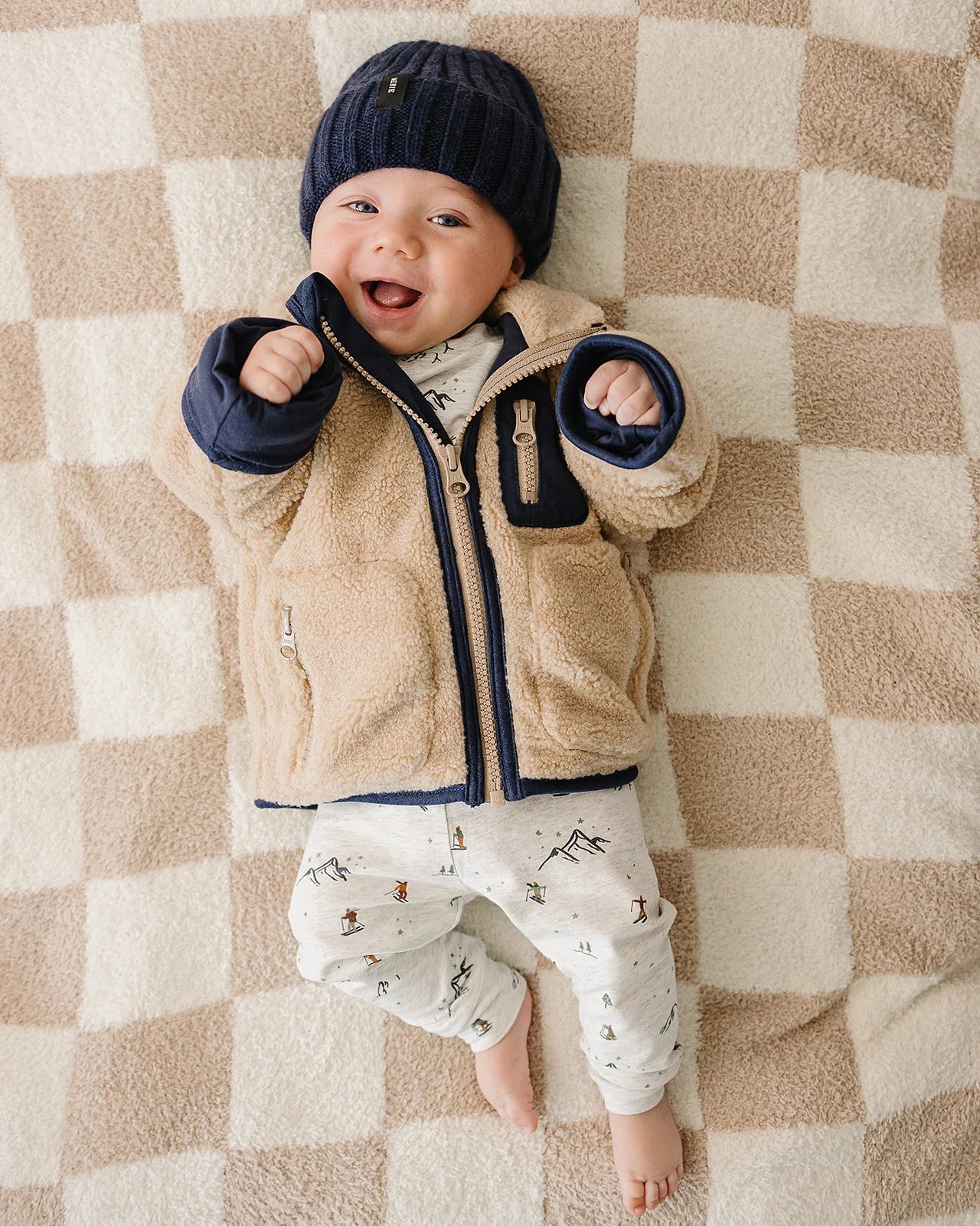 Baby and Kids Sherpa Zip-Up Jacket on a happy baby lying on a cozy blanket, perfect for chilly weather.