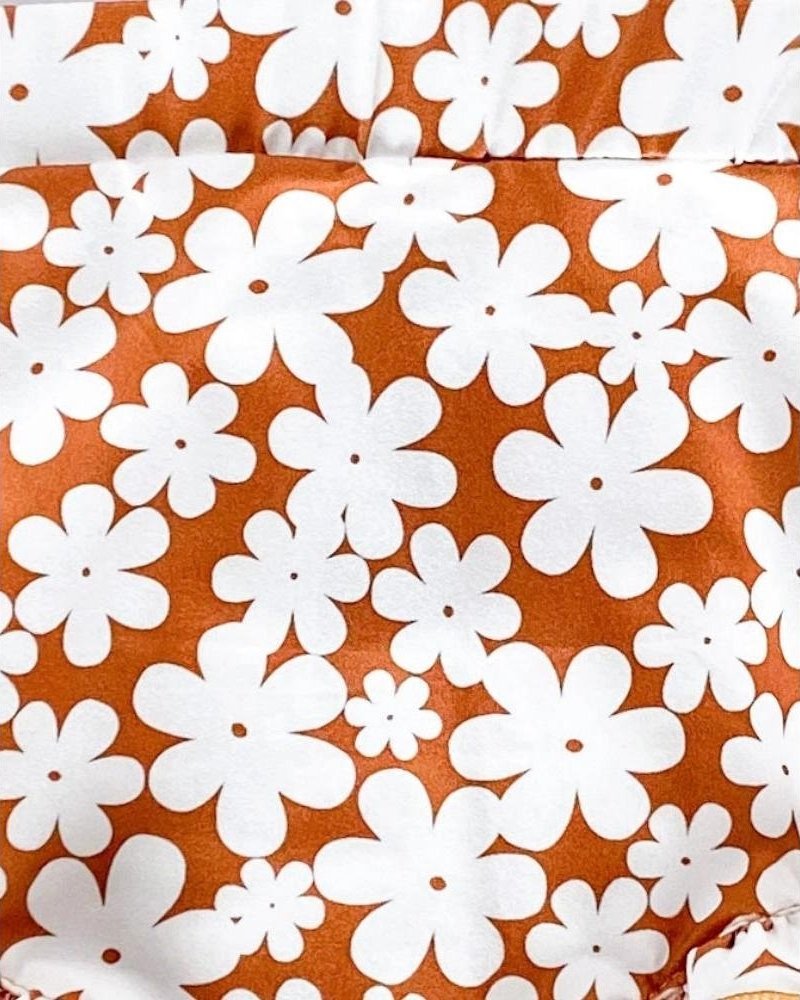 Bohemian floral print featuring white flowers on a vibrant orange background for Andi pleated bell bottom jumpsuit.