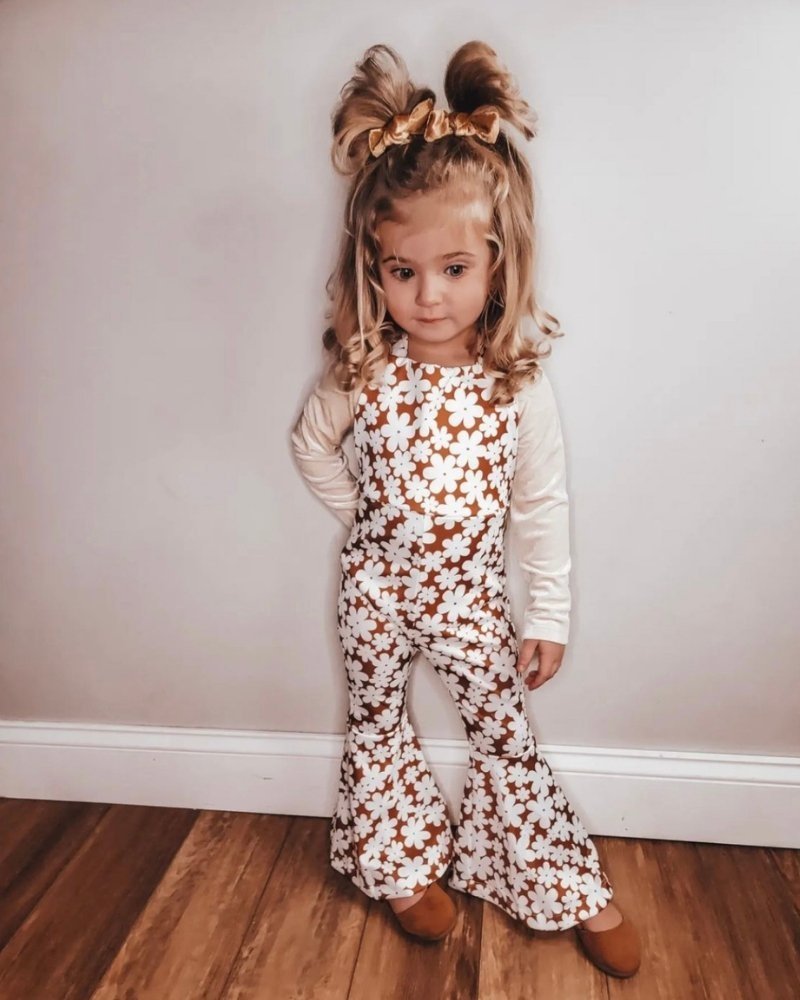 Girl in Andi pleated bell bottom jumpsuit with flower print, showcasing retro style and playful fashion.