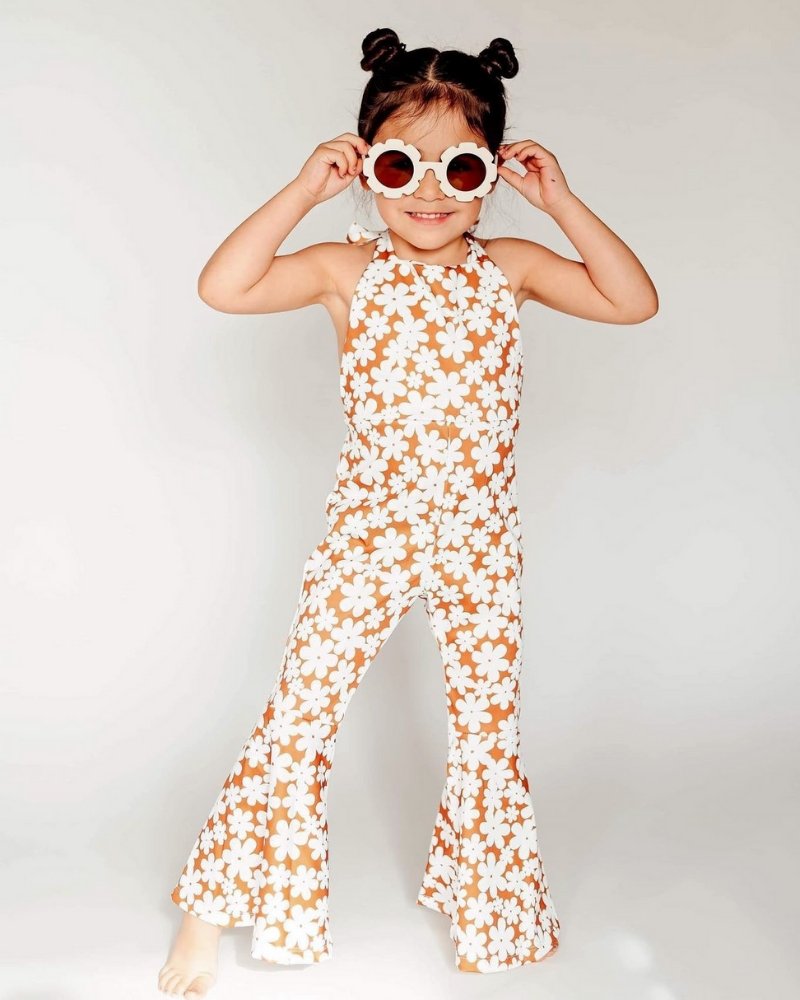 Little girl wearing Andi pleated bell bottom jumpsuit in flower print, posing with sunglasses.