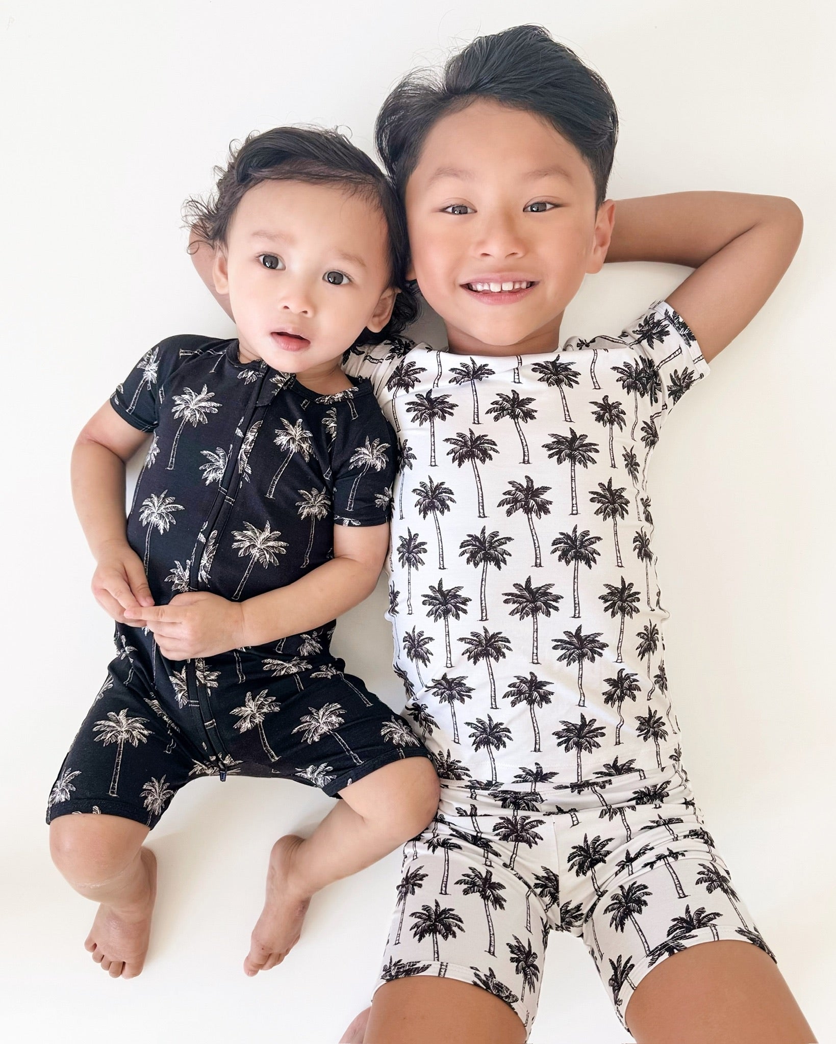 Two children wearing palm print bamboo shorts sets, showcasing a black and white palm design for summer style.