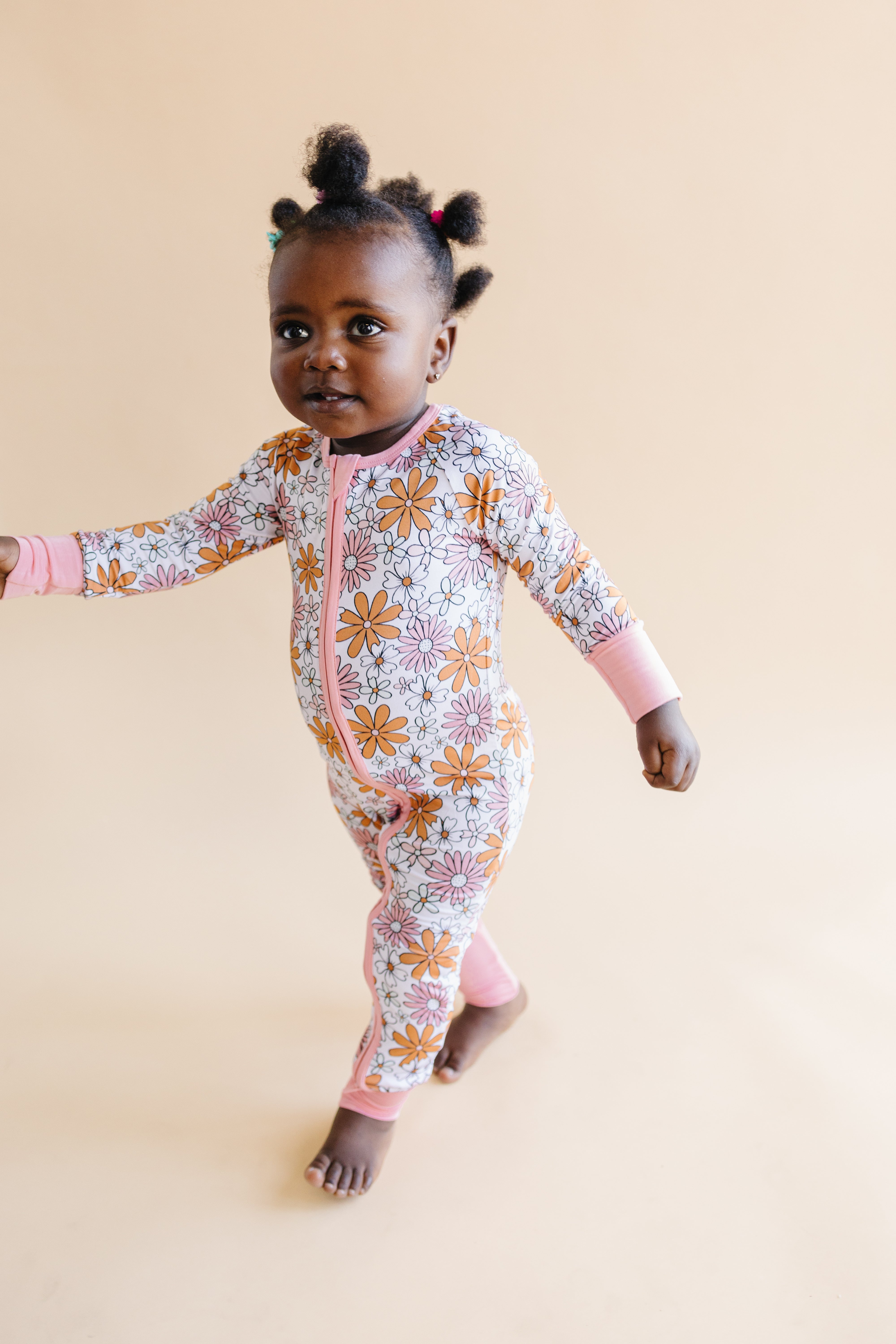 Toddler wearing a floral bamboo zip romper in warm tones, perfect for playtime and comfort.