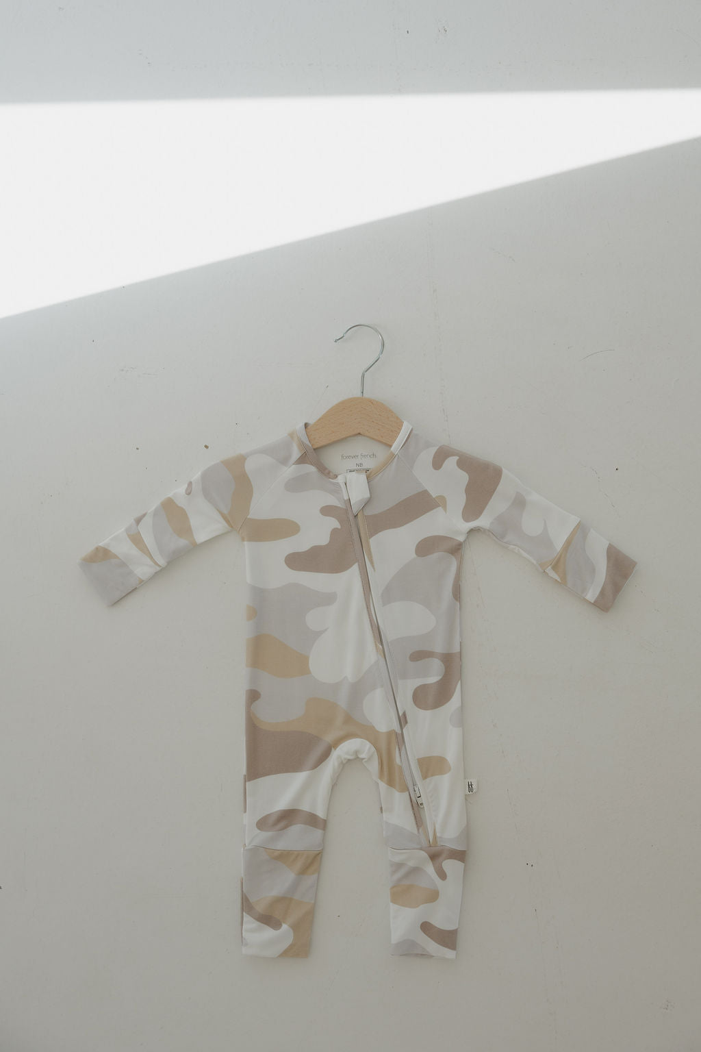 Camo bamboo zip pajamas hanging to showcase soft and stretchy fabric in modern earthy tones.
