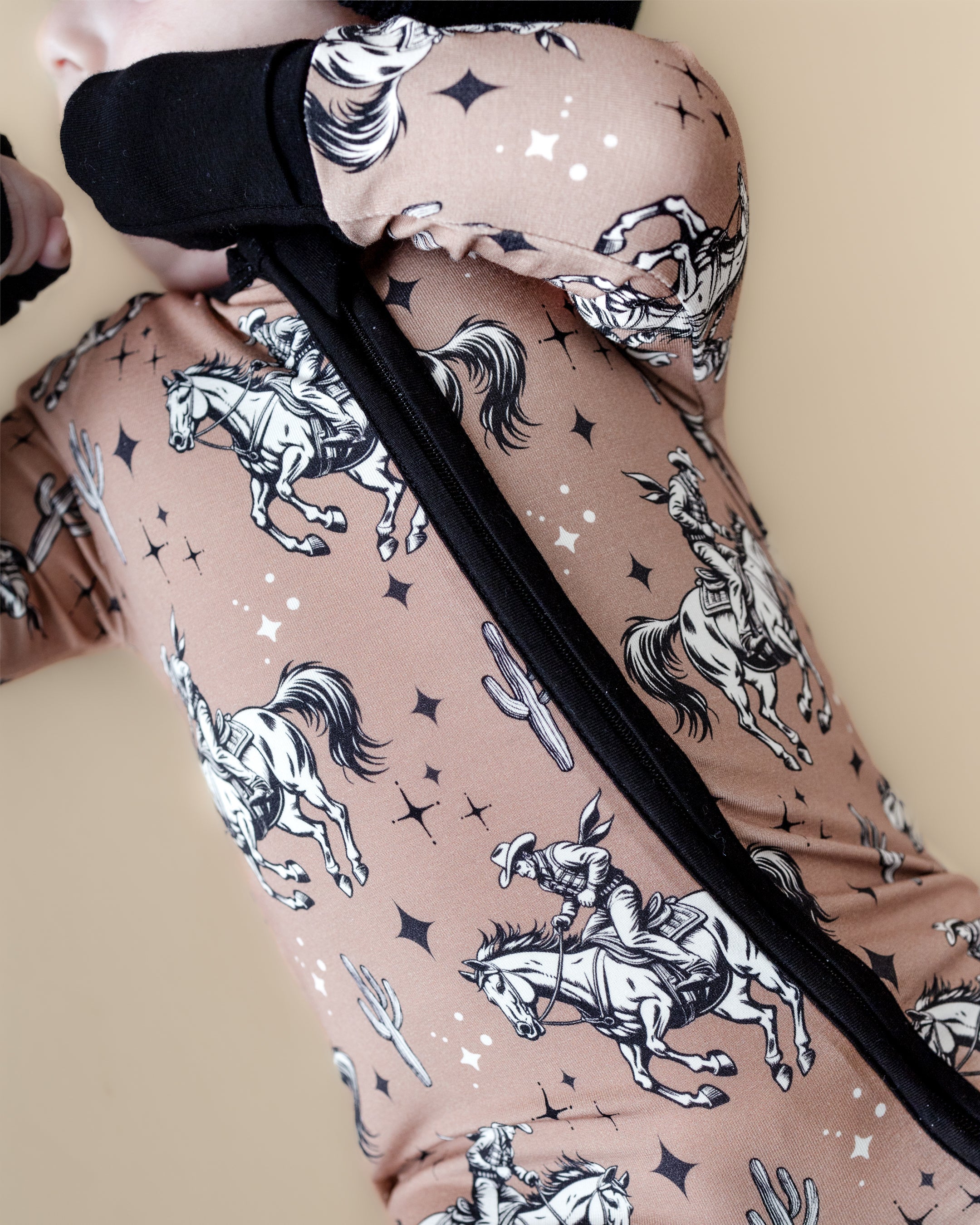 Baby wearing Desert Cowboy bamboo zip romper with cowboy and cactus print for bedtime comfort.