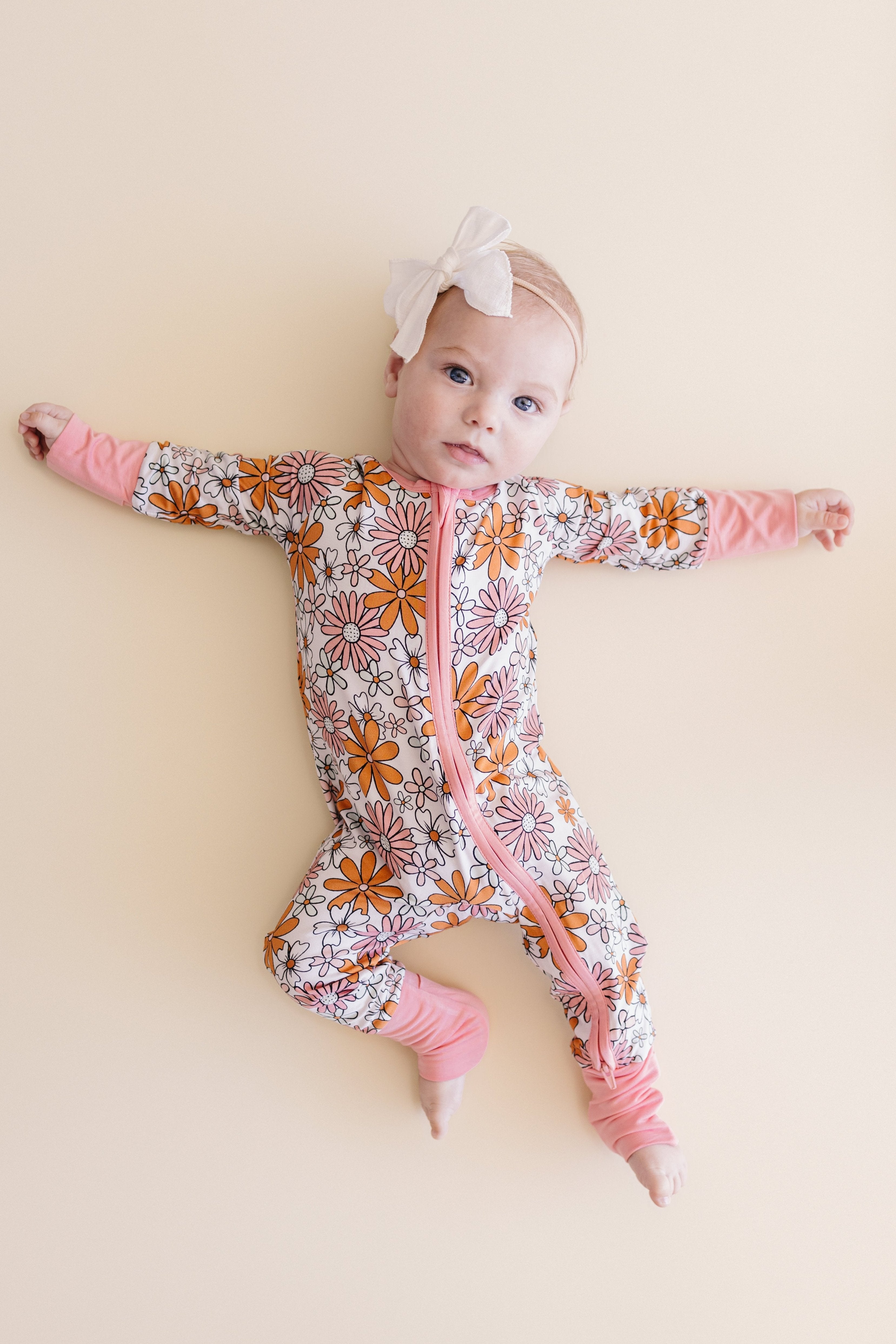 Baby in Retro Garden bamboo zip romper featuring floral print and pink accents on soft background.