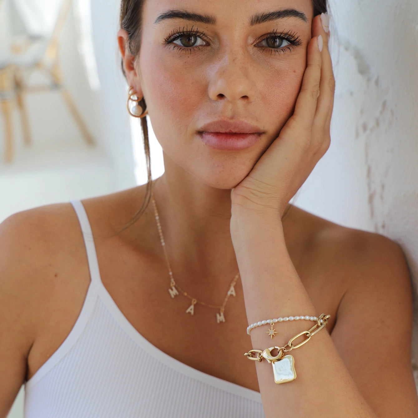 Model wearing a dainty gold mama necklace and trendy bracelets, showcasing minimalist jewelry style.