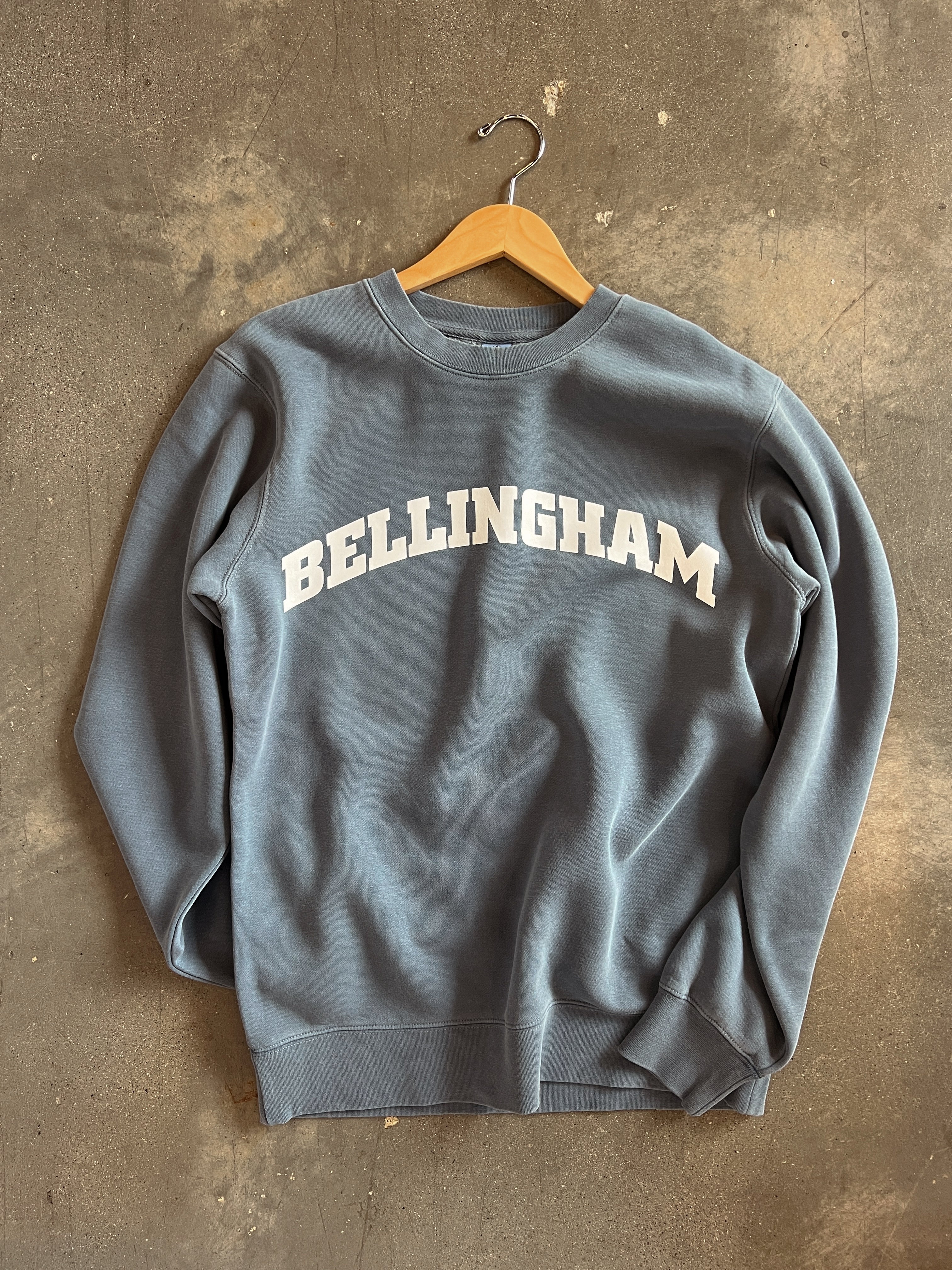 Bellingham adult unisex crewneck sweatshirt in blue with bold white lettering on a hanger.