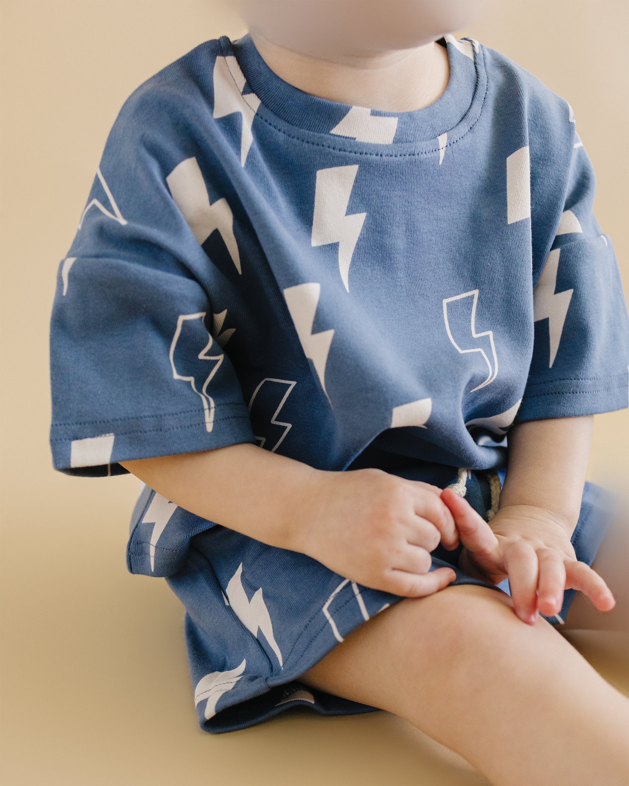 Child wearing blue shorts set with bold white lightning bolt print, perfect for warm weather adventures.